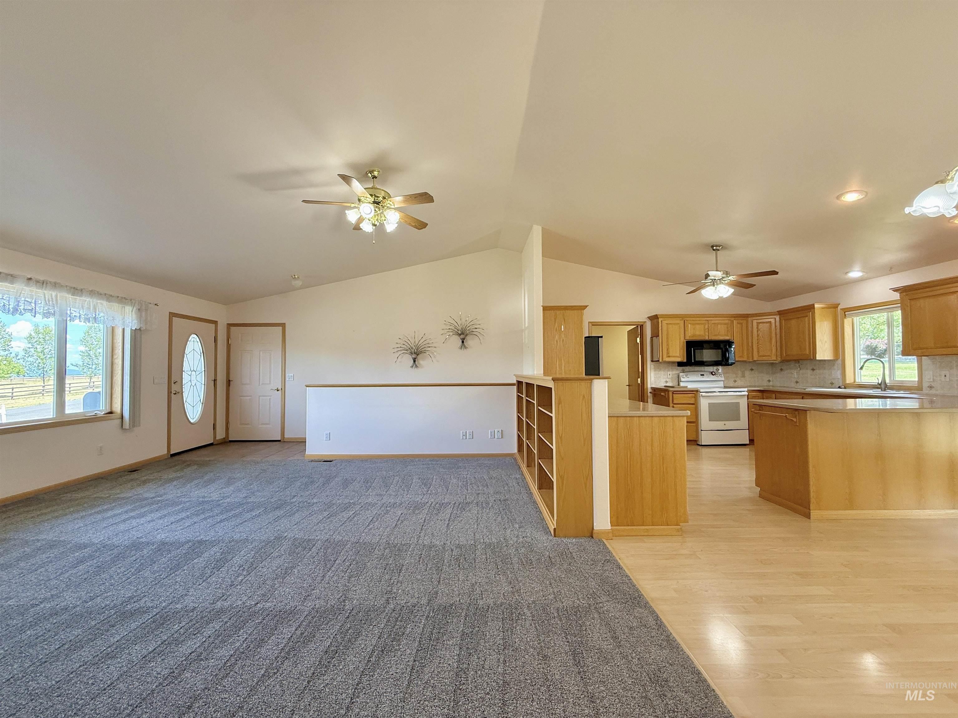 Kitchen featuring a peninsula, white electric range oven, open floor plan, lofted ceiling, and light countertops
