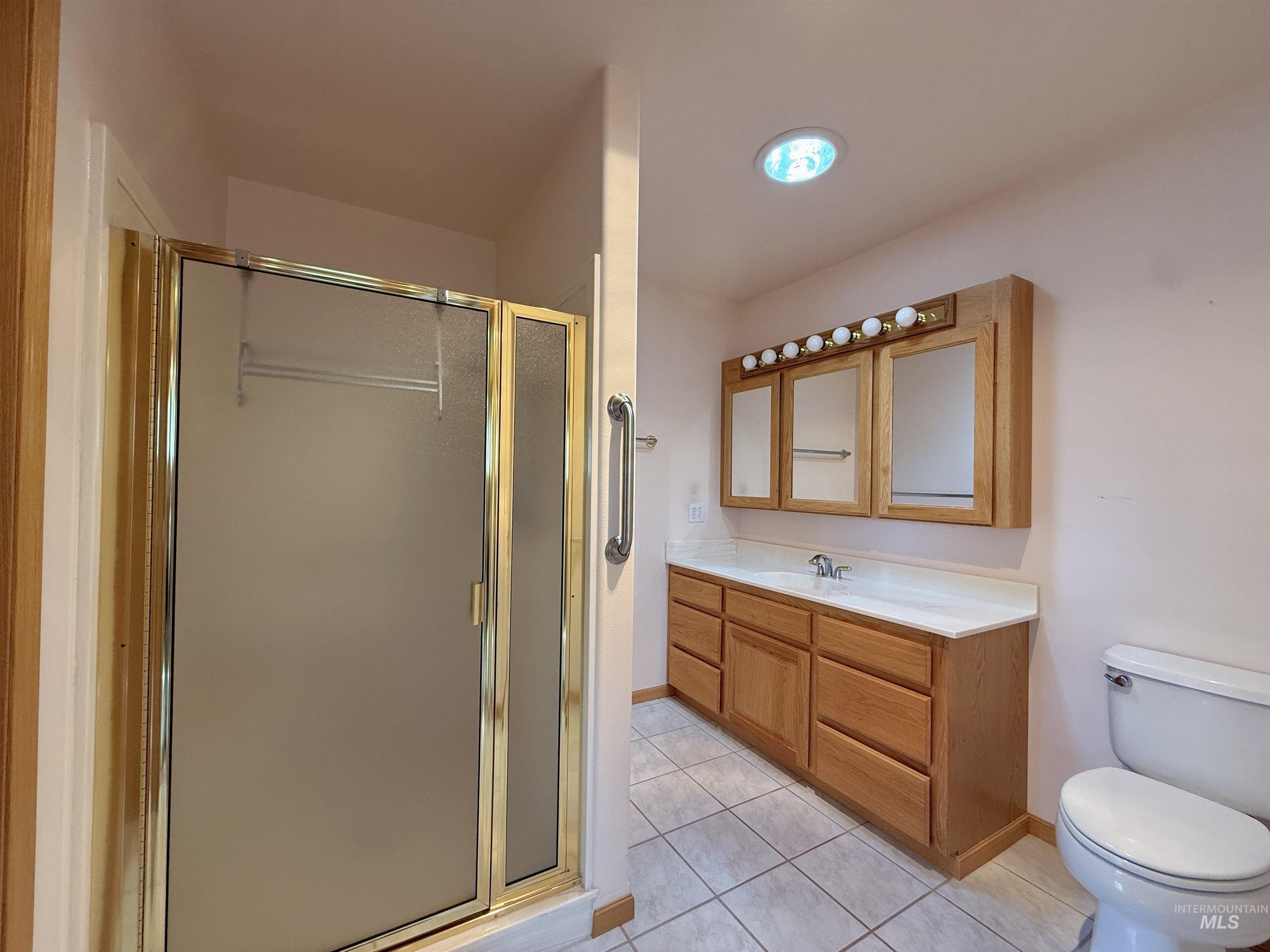 Full bath with tile patterned flooring, vanity, and a stall shower