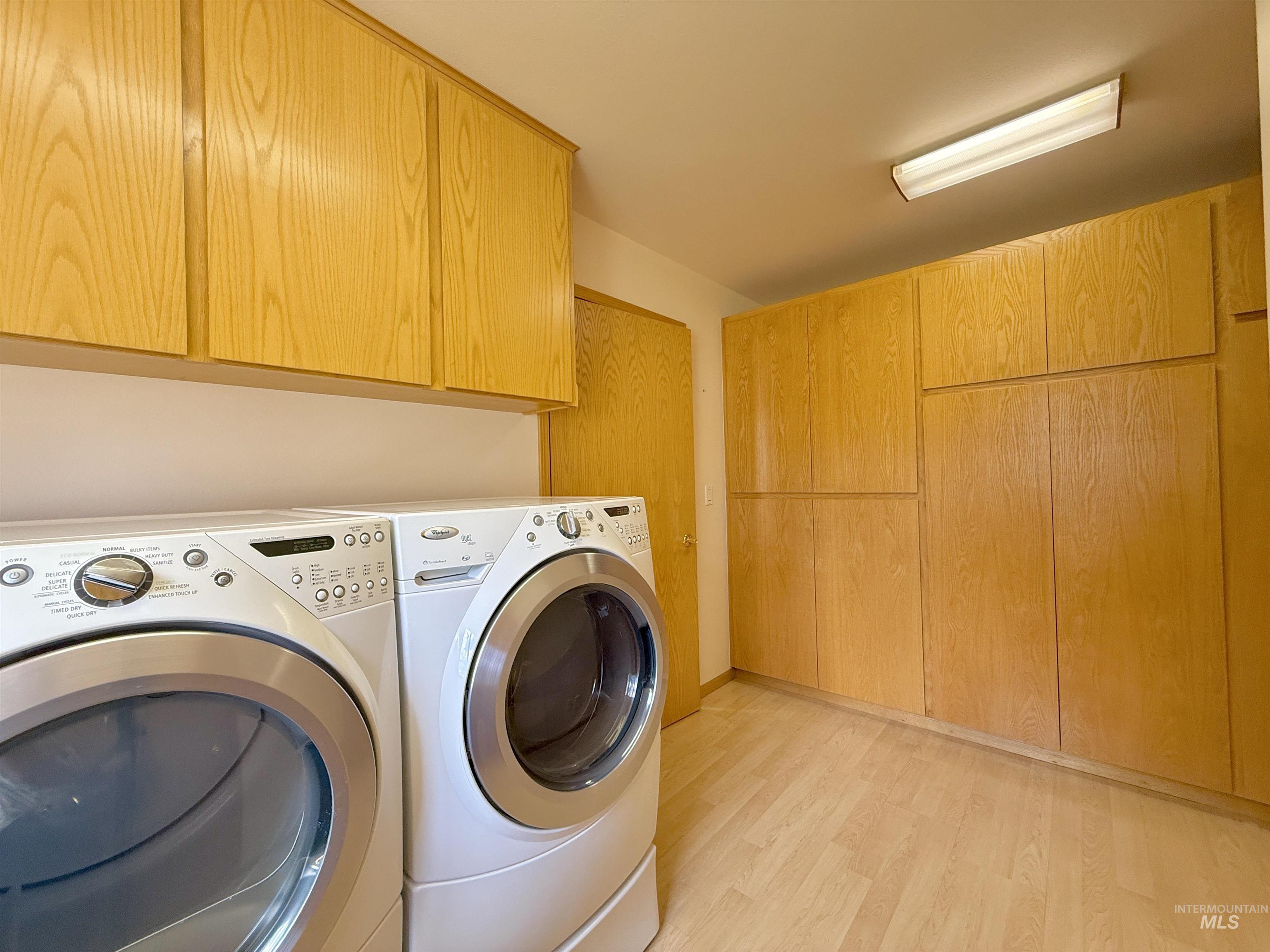 Laundry room featuring cabinet space, washer and clothes dryer, and light wood-style floors