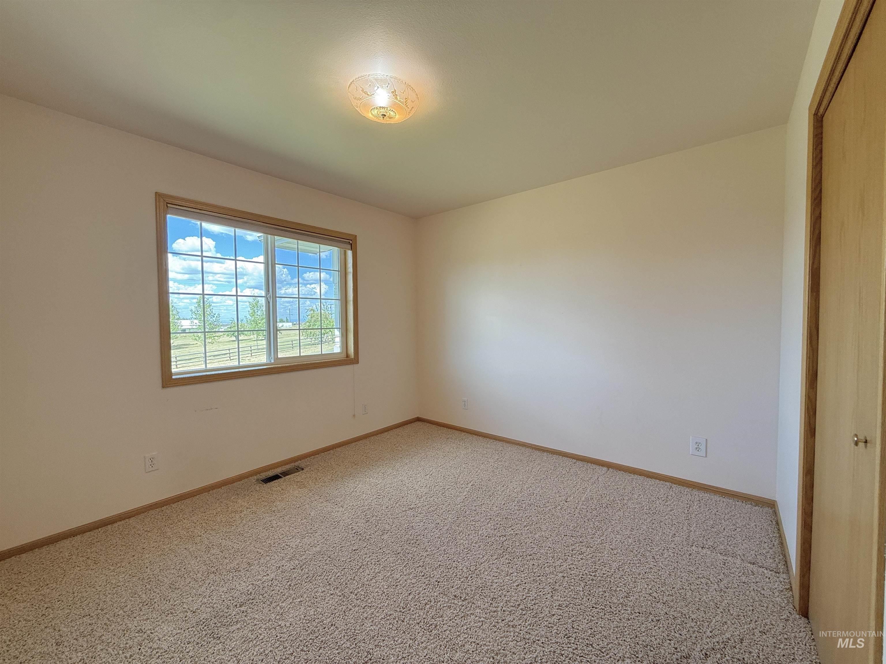 Empty room with light colored carpet and baseboards