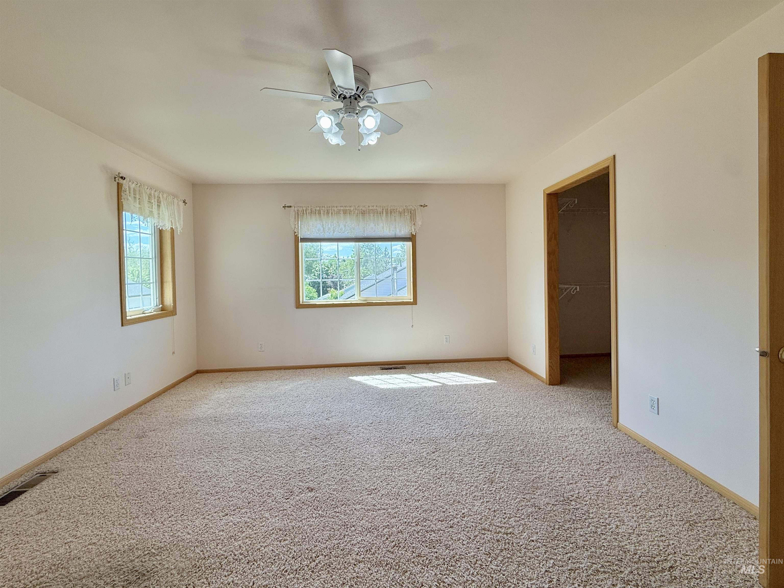 Carpeted spare room with baseboards and a ceiling fan