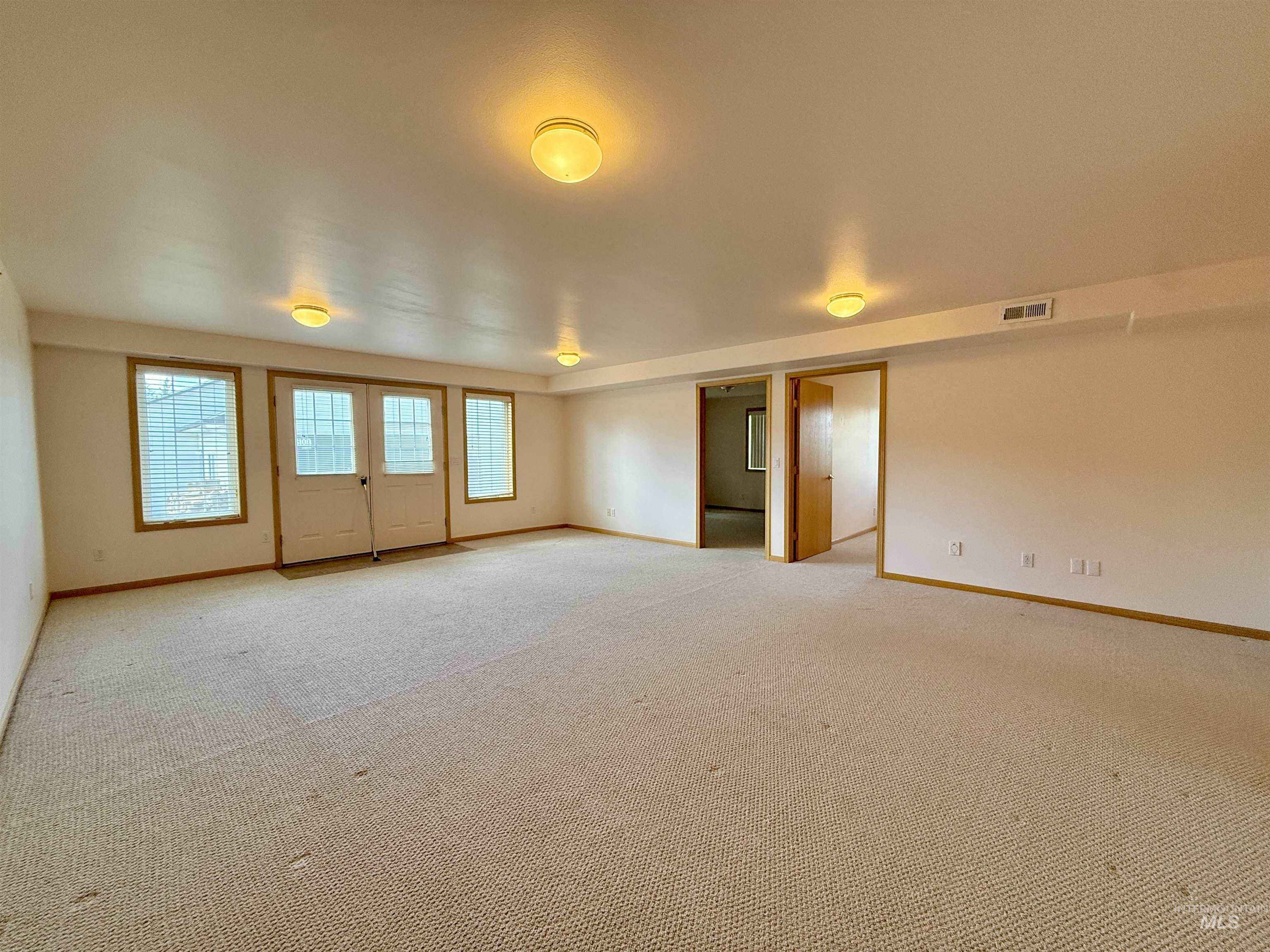 Unfurnished room with baseboards and light colored carpet