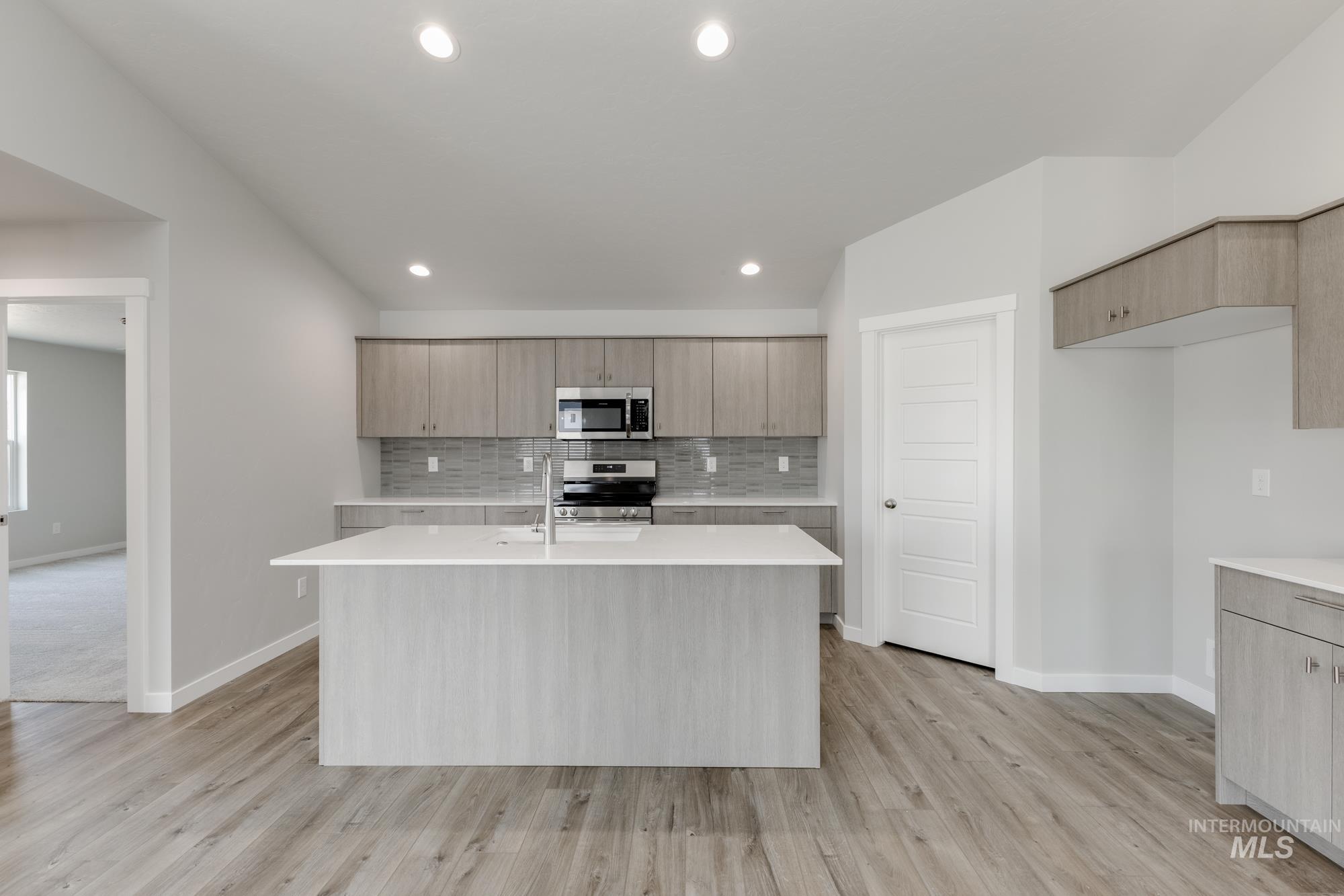 Kitchen featuring backsplash, an island with sink, stainless steel appliances, modern cabinets, and recessed lighting