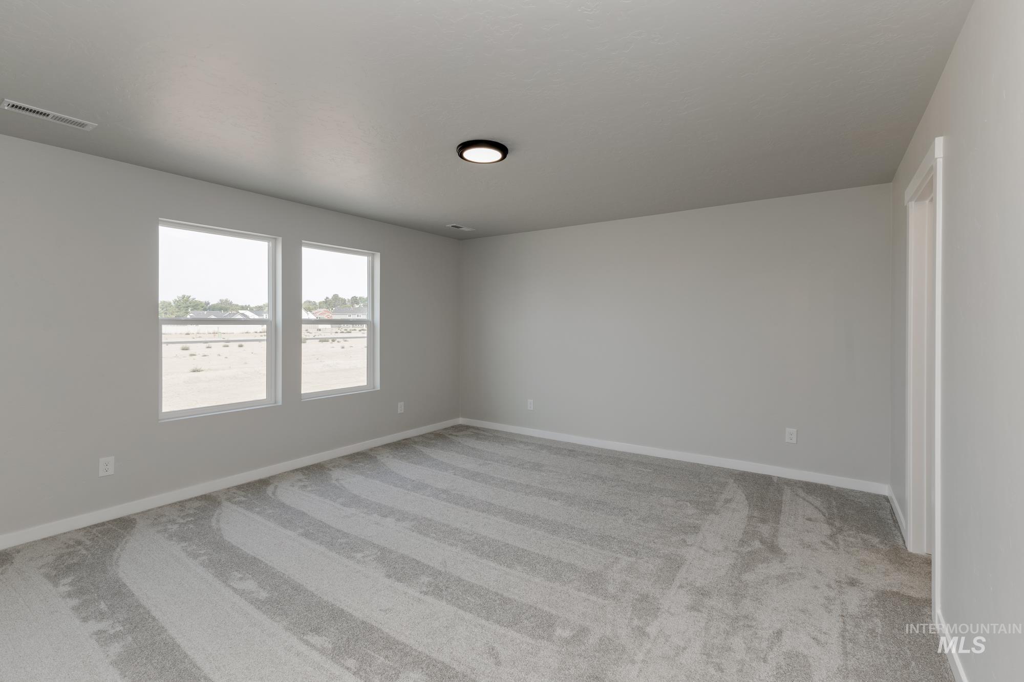 Empty room featuring light colored carpet and baseboards