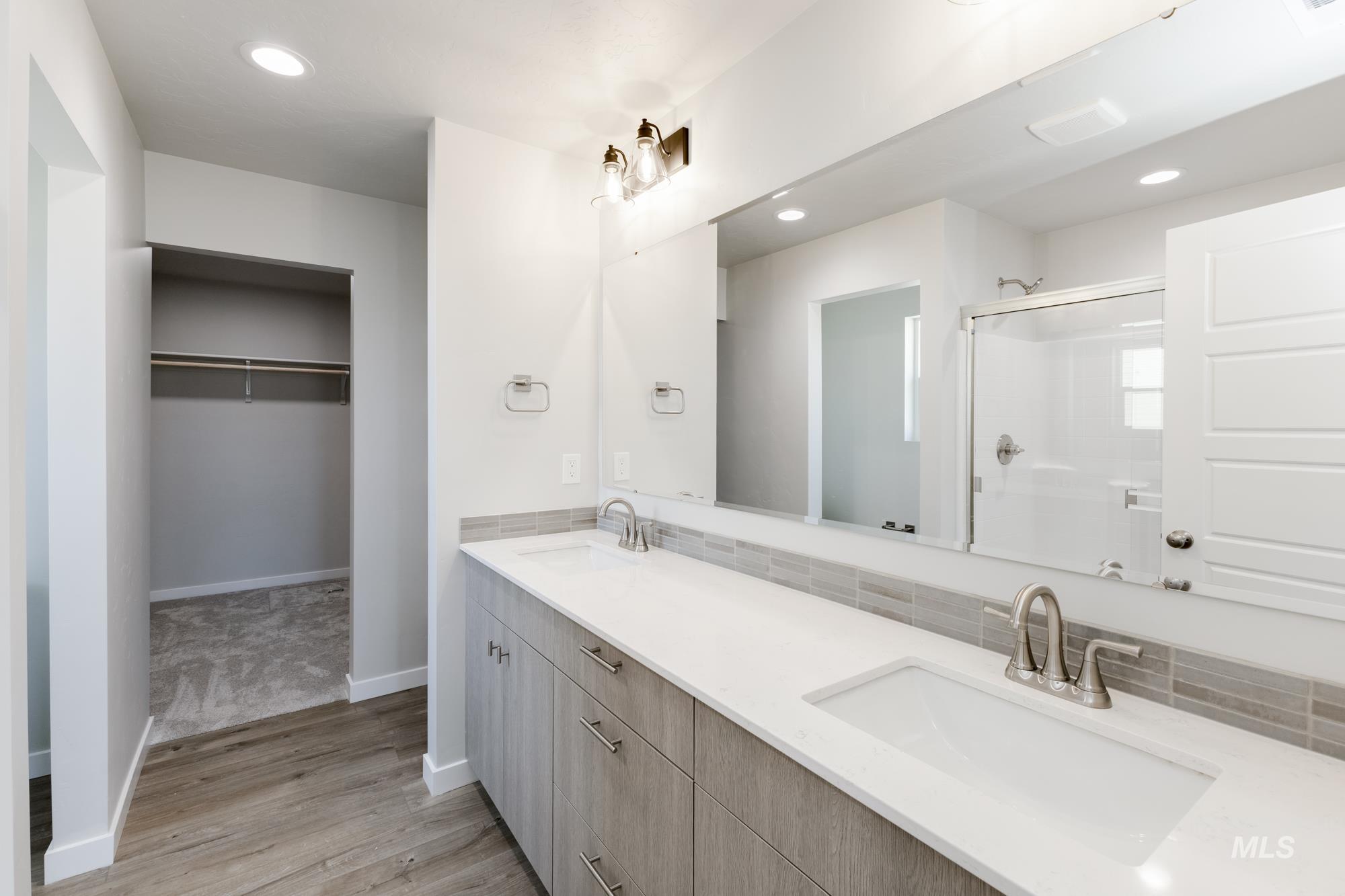 Bathroom featuring double vanity, recessed lighting, a shower stall, light wood-style floors, and a spacious closet