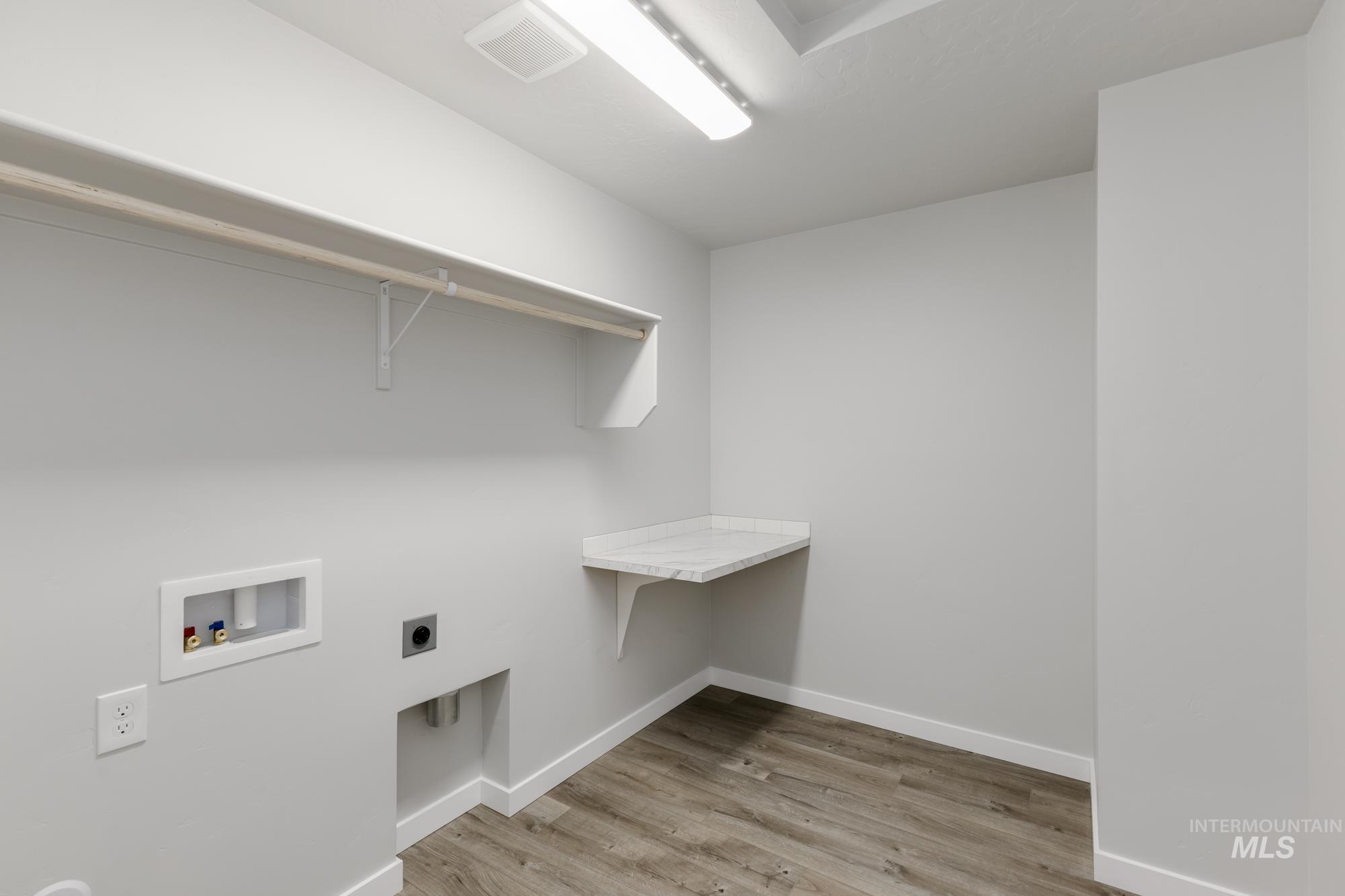 Laundry area featuring light wood-type flooring, washer hookup, and electric dryer hookup