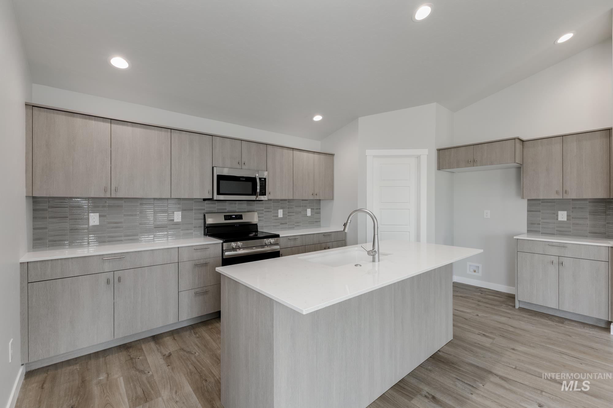 Kitchen with decorative backsplash, light stone countertops, appliances with stainless steel finishes, modern cabinets, and light wood-style flooring