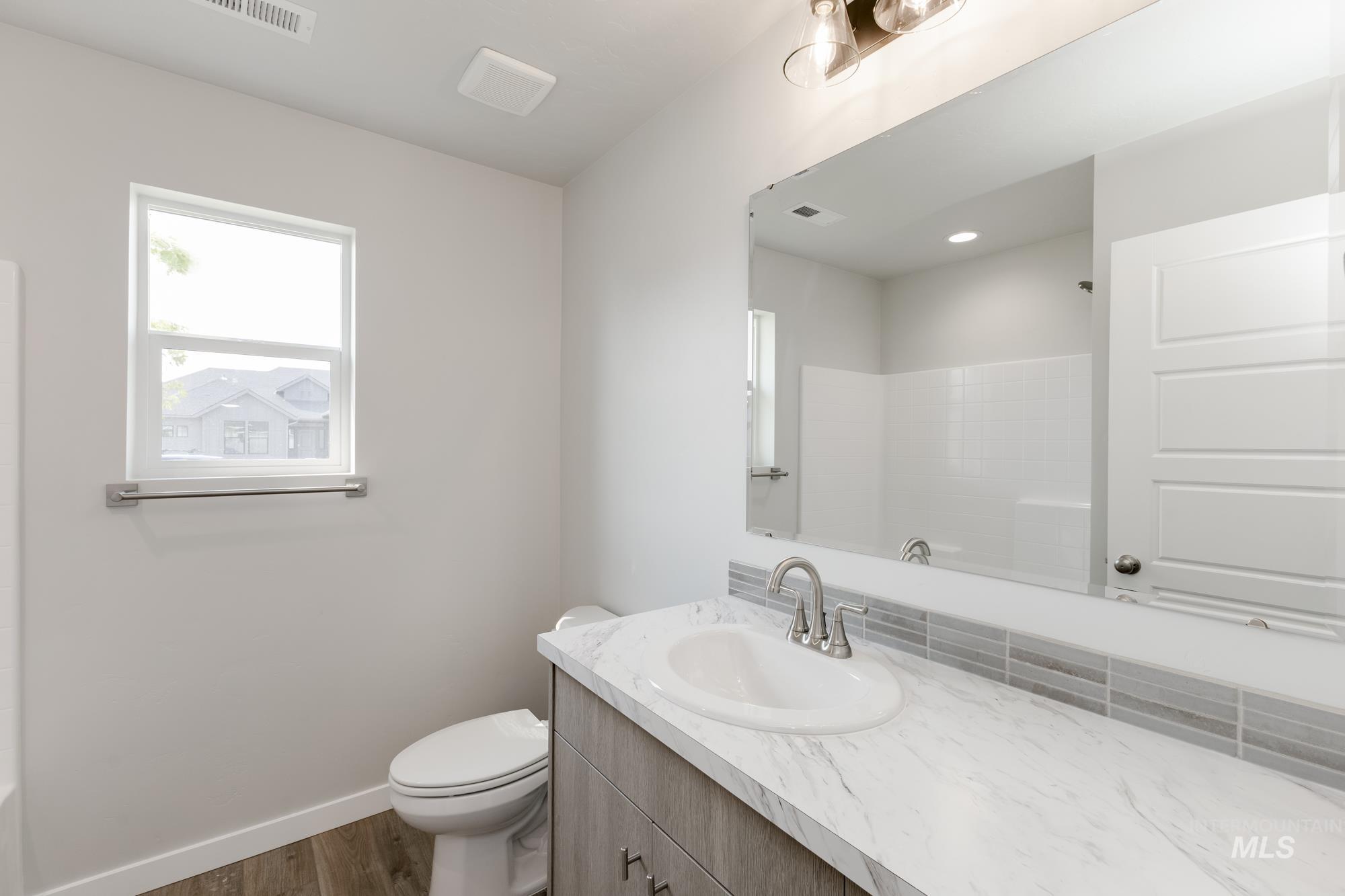 Full bathroom featuring dark wood finished floors, vanity, and a shower