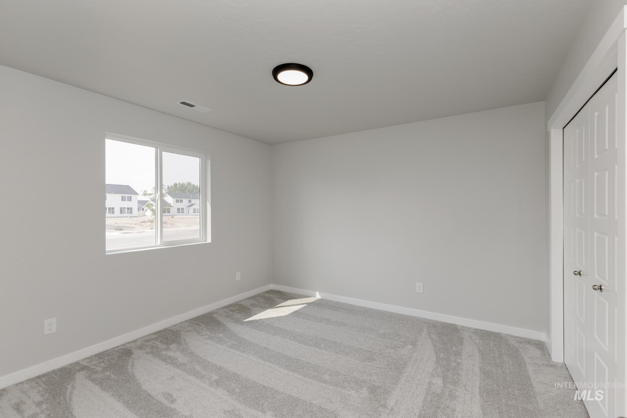 Unfurnished bedroom with light carpet and a closet