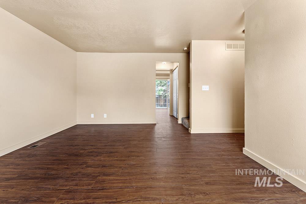Spare room featuring dark wood finished floors, a textured ceiling, and a textured wall