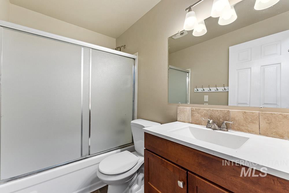 Bathroom with vanity, tasteful backsplash, and enclosed tub / shower combo