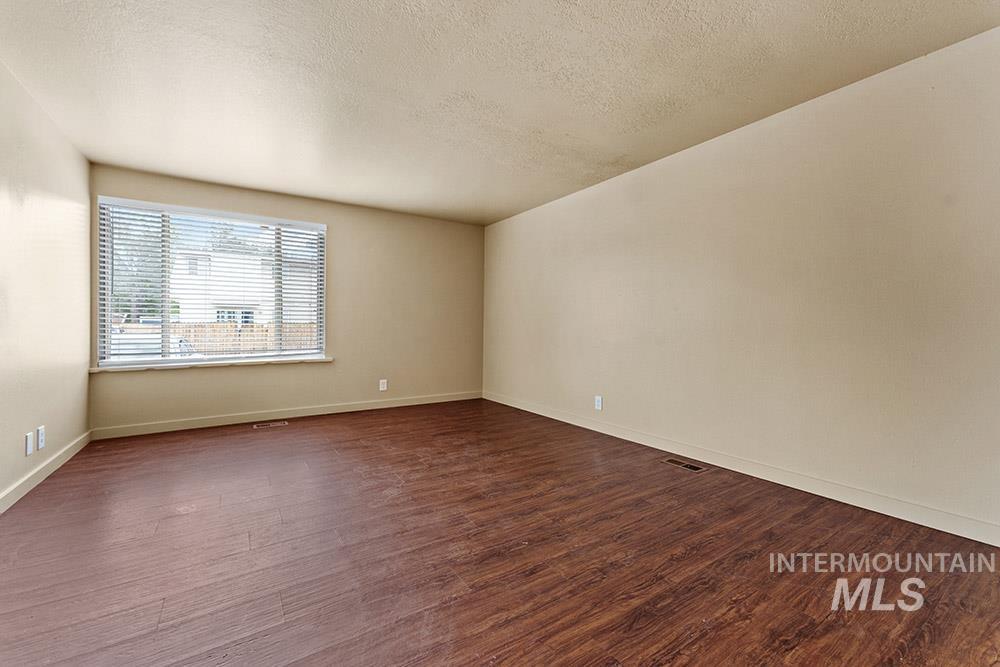 Spare room featuring a textured ceiling and dark wood finished floors