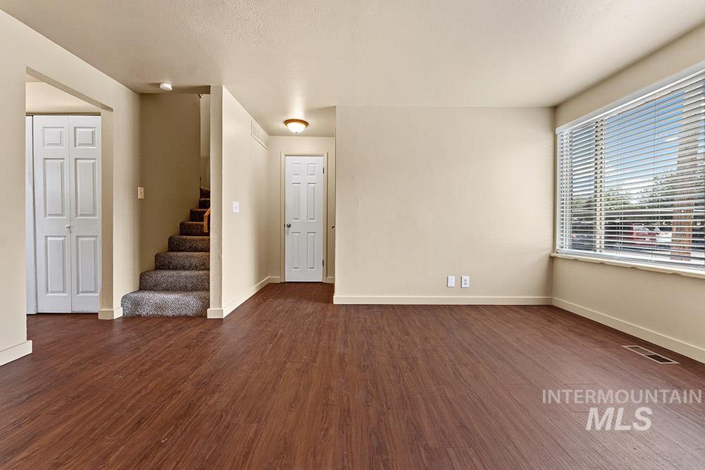 Unfurnished room with stairs, dark wood-type flooring, and a textured ceiling
