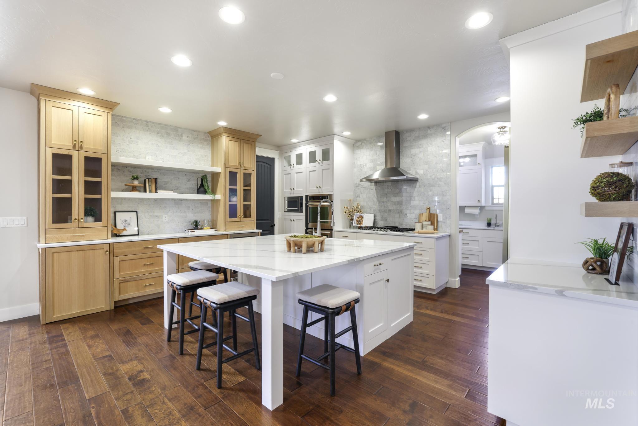 Kitchen featuring open shelves, light stone countertops, arched walkways, a breakfast bar, and dark wood-style floors