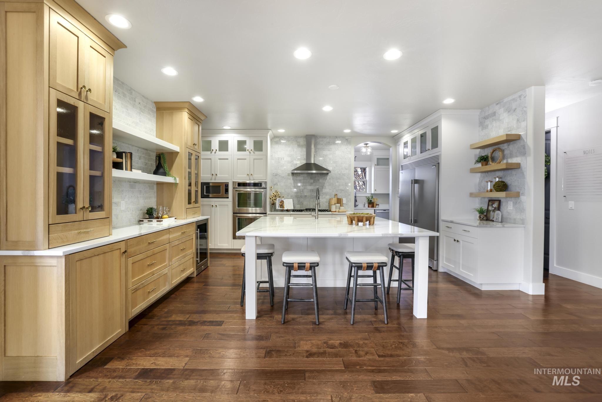 Two tone kitchen with open shelves, tasteful backsplash, glass insert cabinets, dark wood finished floors, and recessed lighting