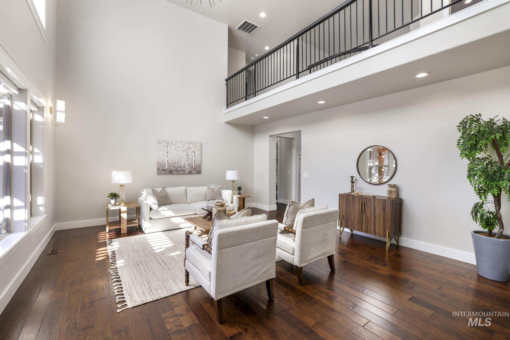 Living room featuring dark wood-style flooring, a high ceiling, and recessed lighting