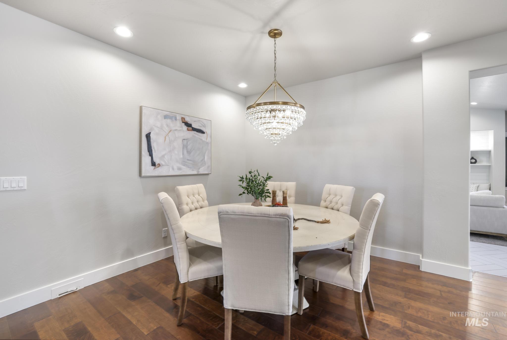 Dining room with dark wood-style flooring and hanging lights