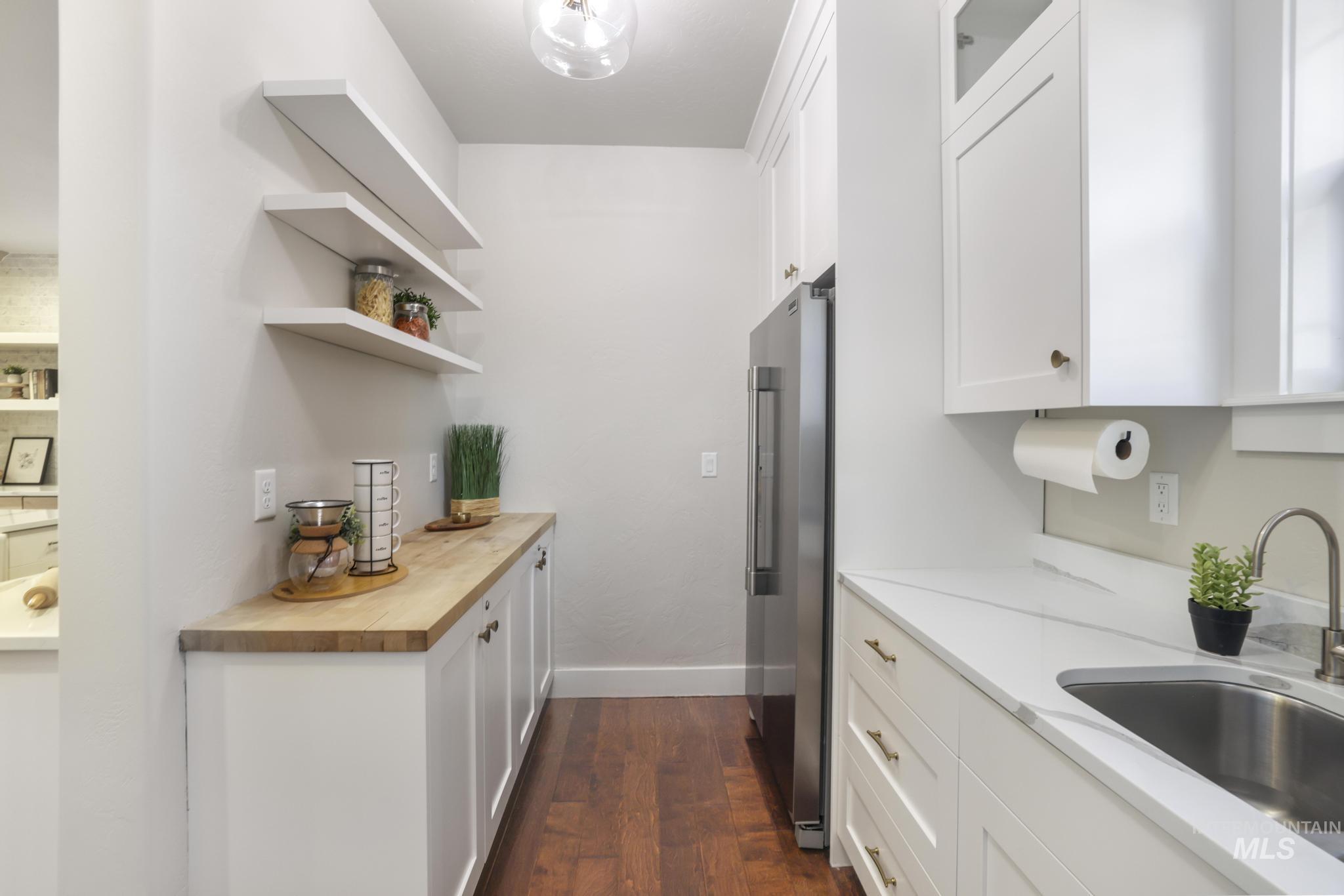 Kitchen featuring white cabinets, open shelves, high quality fridge, dark wood-style floors, and butcher block countertops