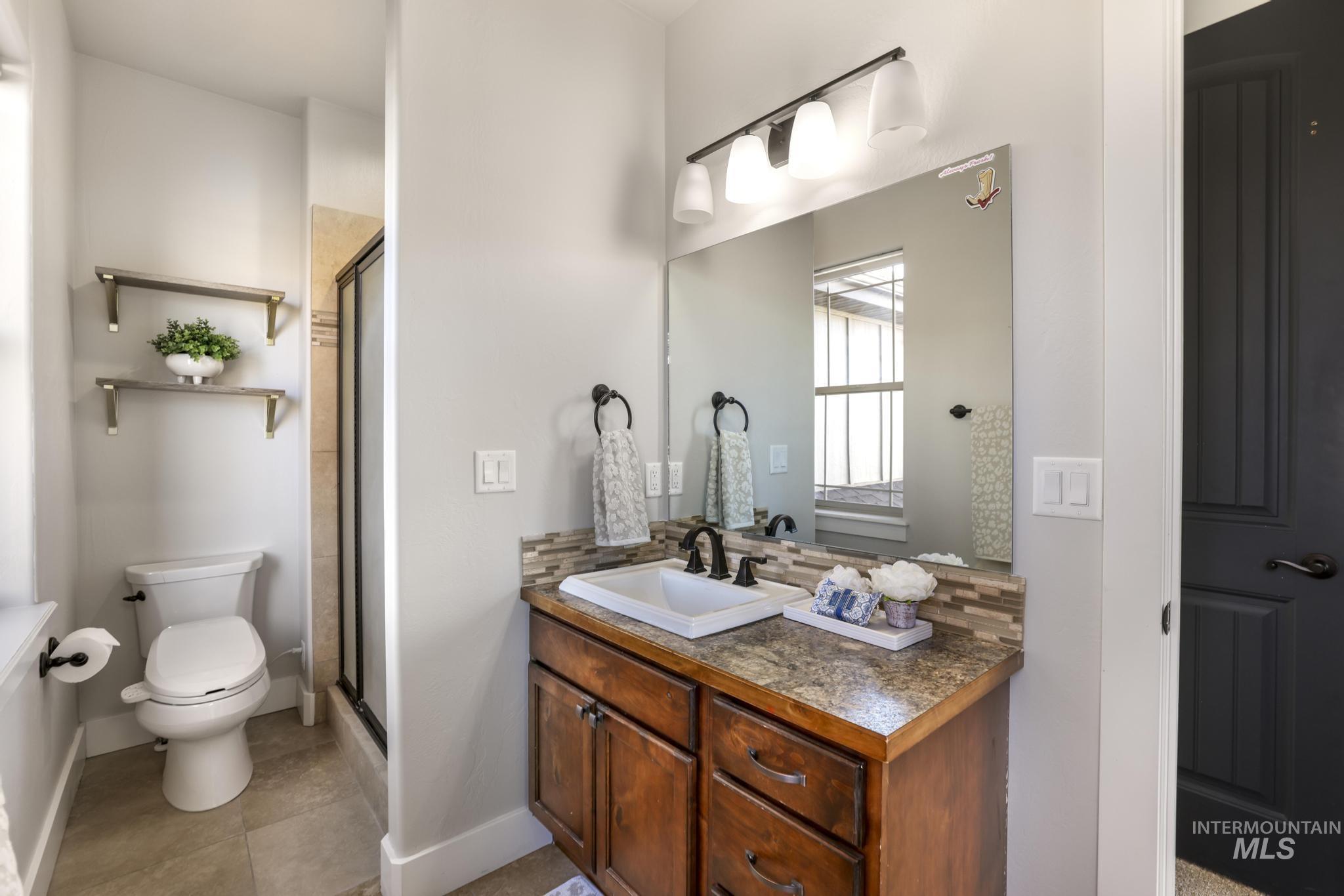 Full bathroom featuring vanity, a stall shower, light tile patterned floors, and decorative backsplash