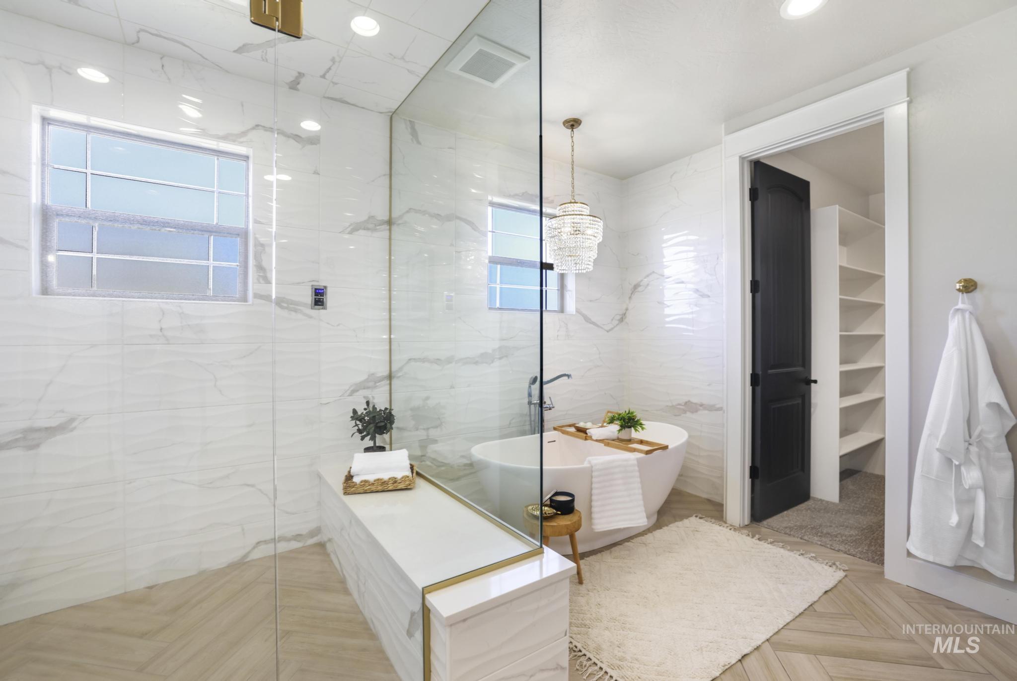 Bathroom with a marble finish shower, tile walls, a freestanding bath, parquet floors, and a walk in closet