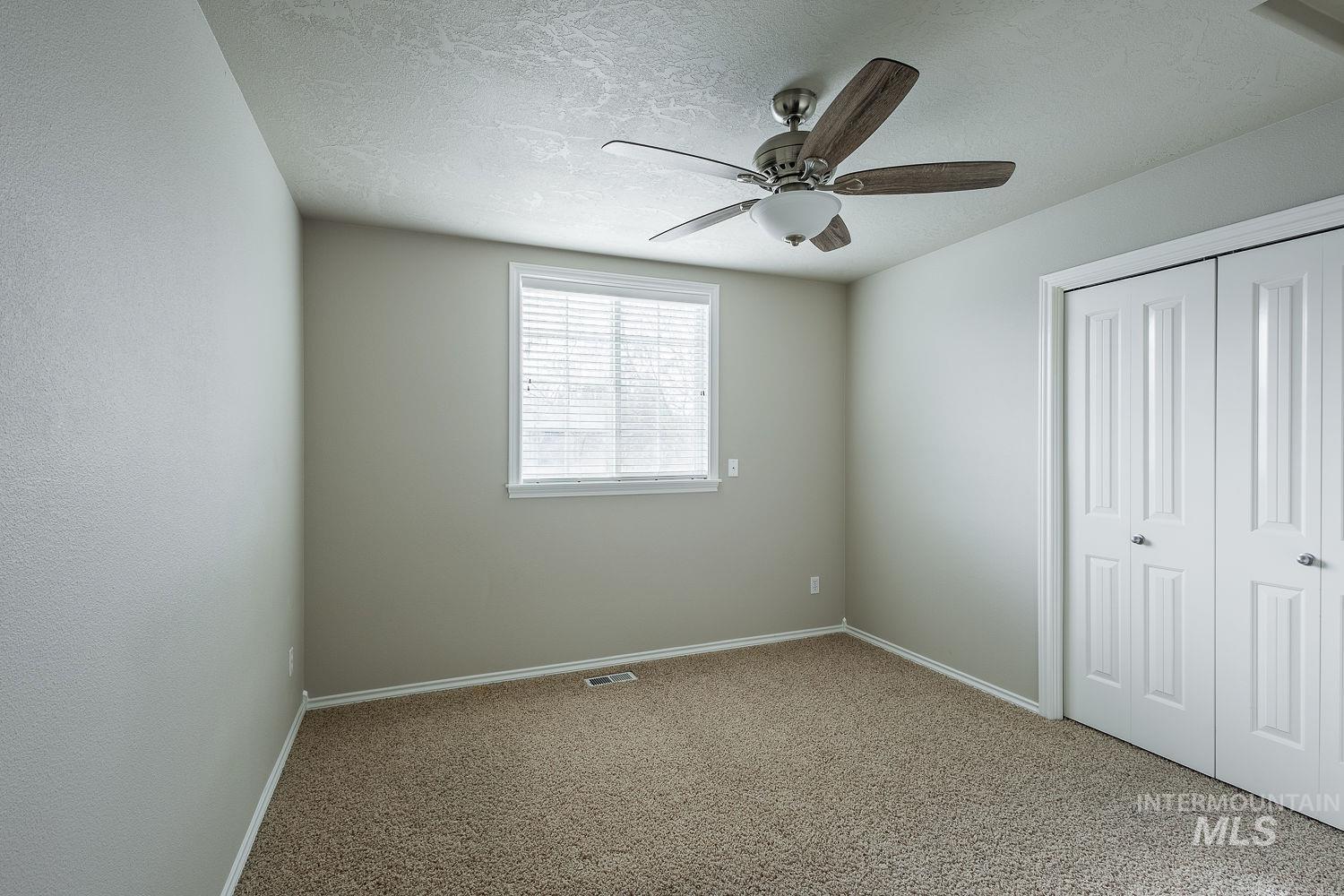 Unfurnished bedroom featuring carpet, a closet, a ceiling fan, and a textured ceiling