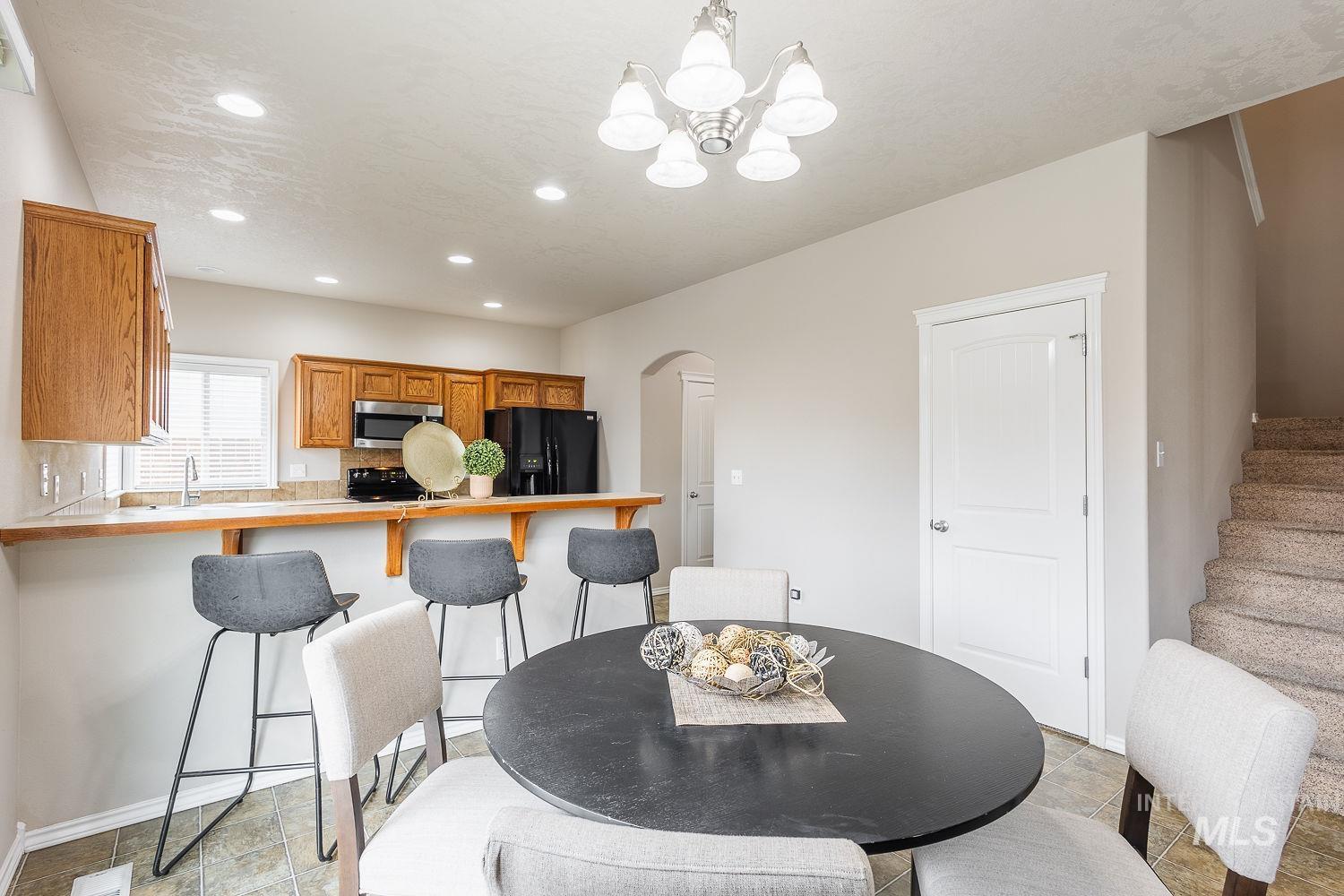 Dining space with arched walkways, stairs, recessed lighting, and a chandelier