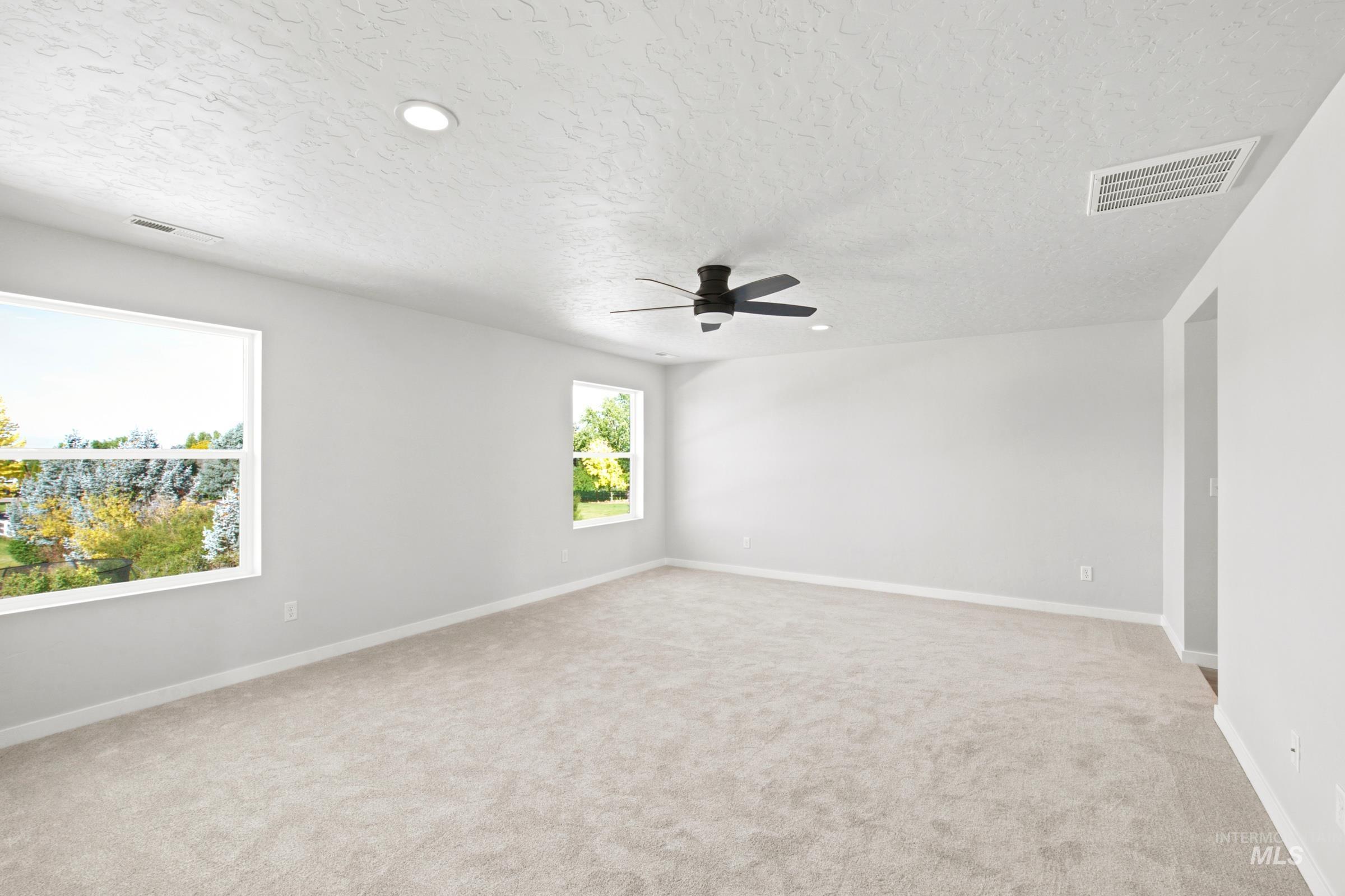 Spacious room featuring neutral carpeting, recessed lighting, and a ceiling fan