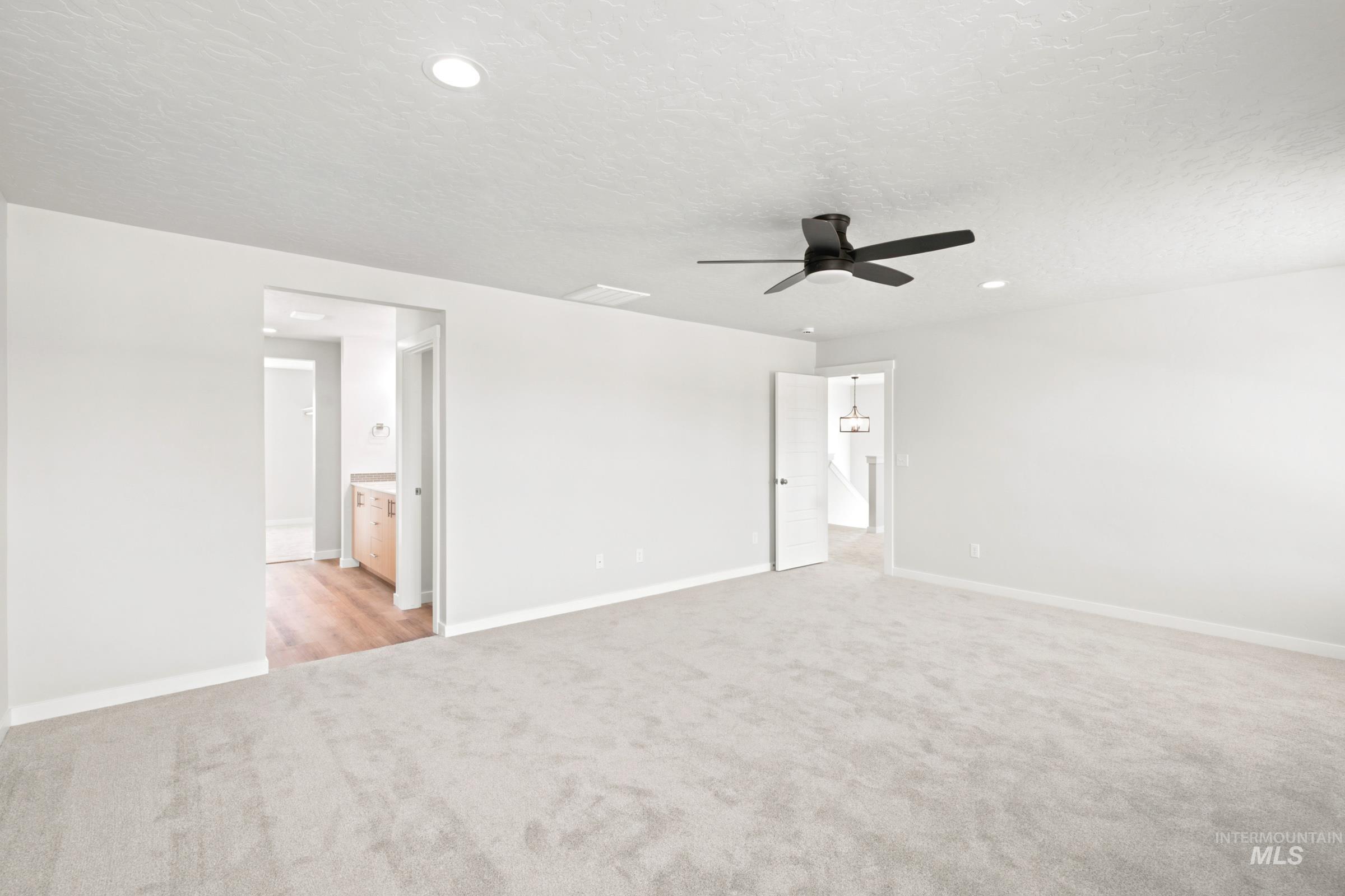 Spacious carpeted room featuring a matte black ceiling fan, recessed lighting, and bright white walls