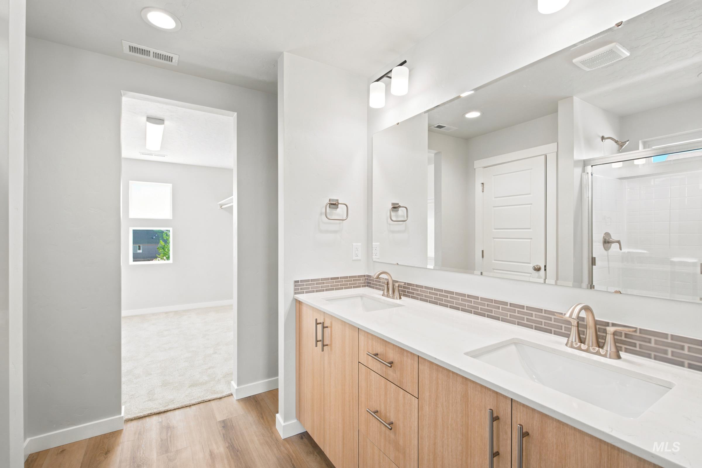 Bathroom featuring a double vanity with light wood-finish cabinetry, white countertops, and brushed nickel fixtures