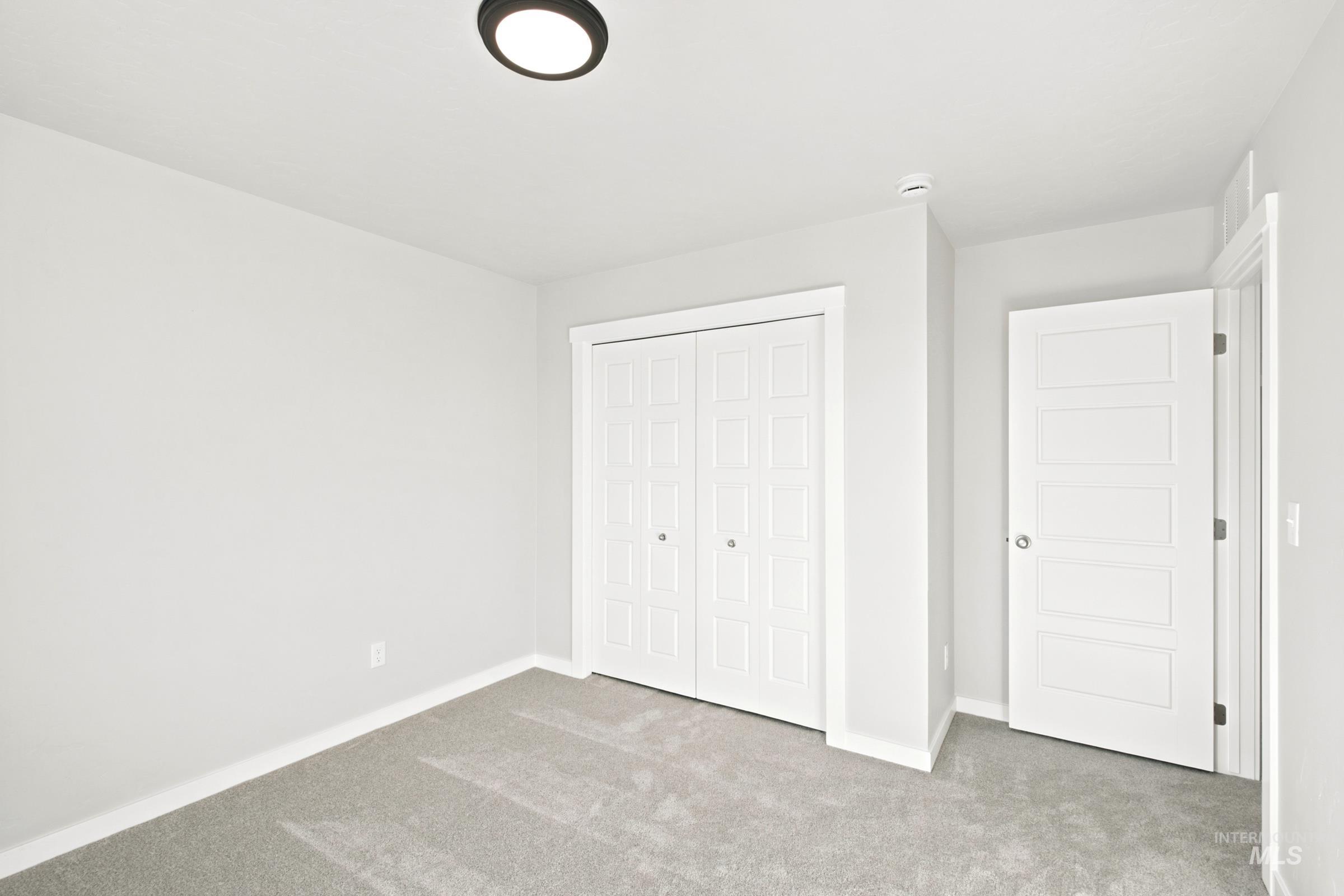 Neutral-toned interior room featuring light gray walls, gray carpet flooring, and white trim
