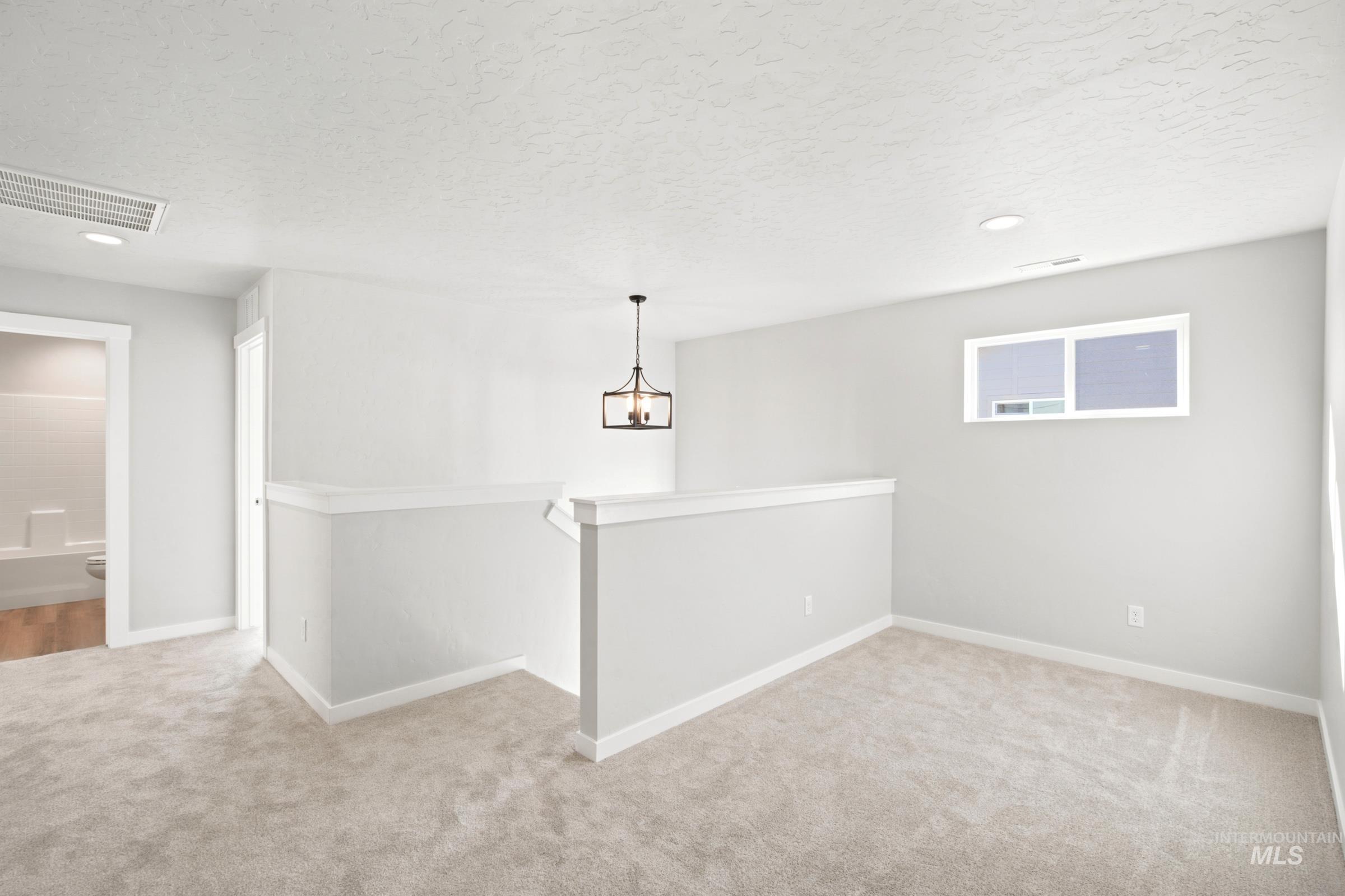 Upper-level landing featuring neutral carpeting, recessed lighting, and a contemporary chandelier