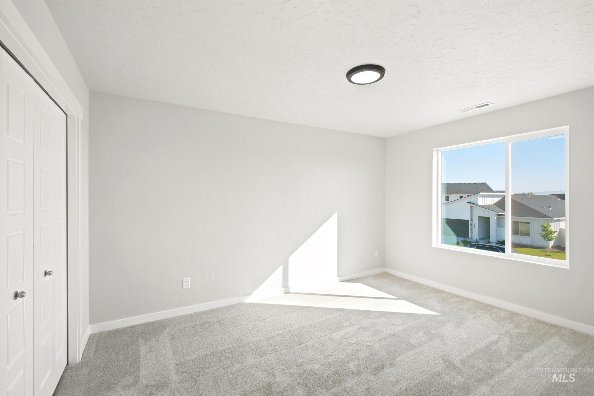 Spacious room with light gray carpeting, a large window, and white trim
