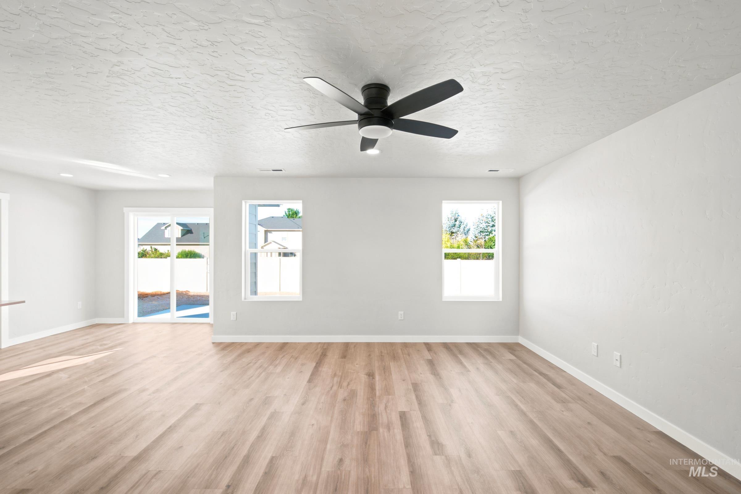 Spacious room featuring wood-finish flooring, light gray walls, and a textured white ceiling