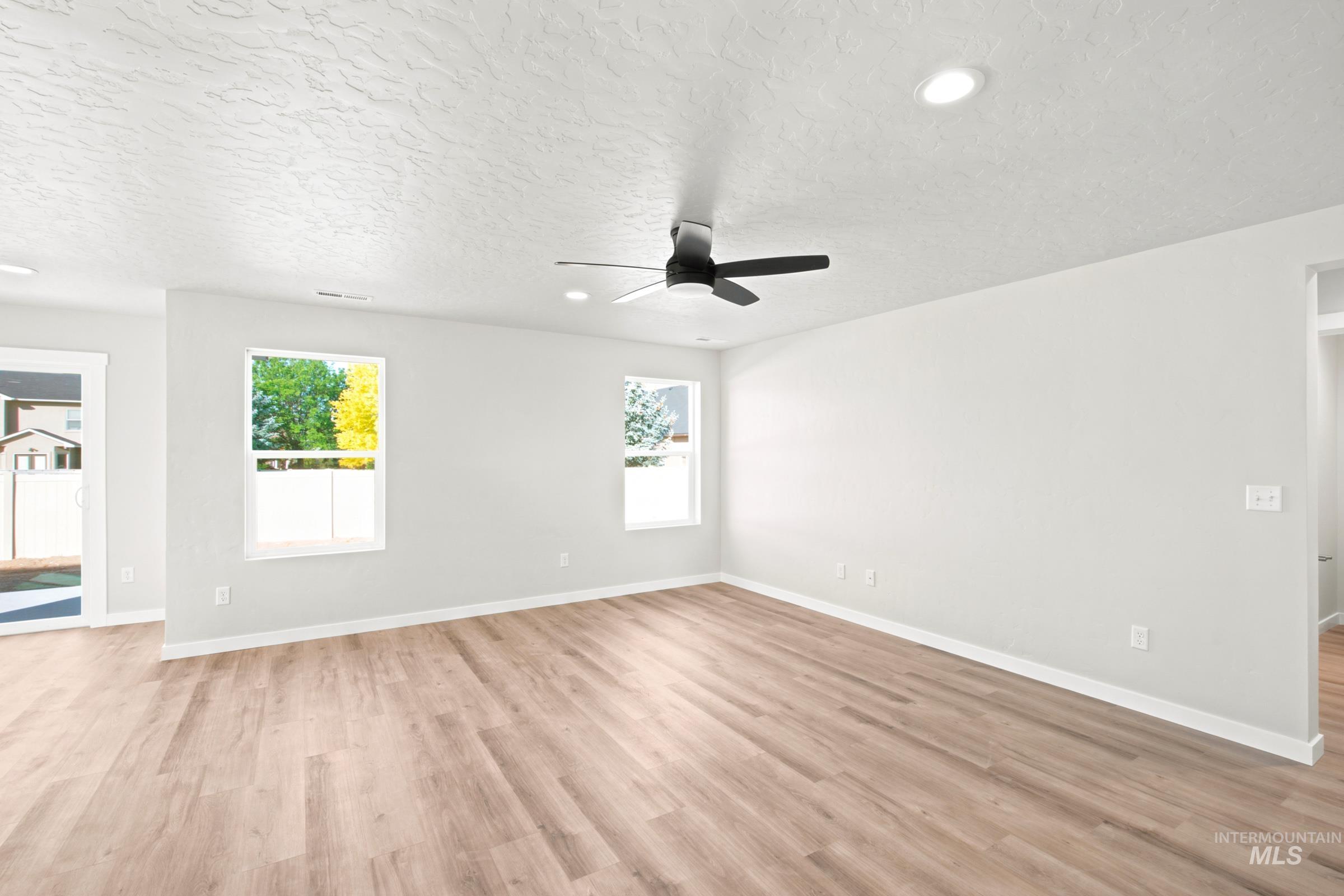 Spacious interior featuring light wood-finish flooring, white walls, and a textured white ceiling