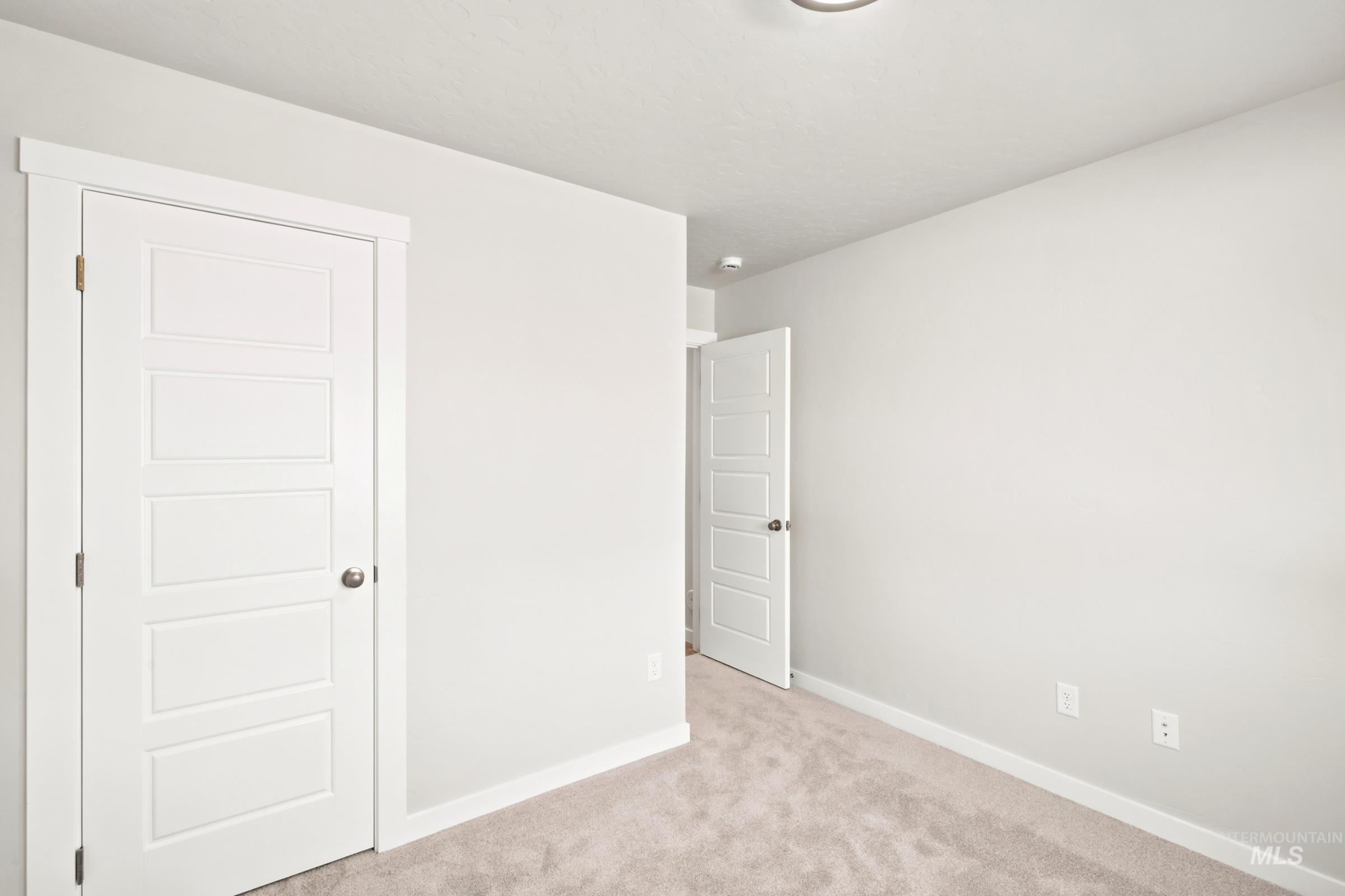 Interior room featuring light gray carpeting, white baseboards, and neutral wall paint
