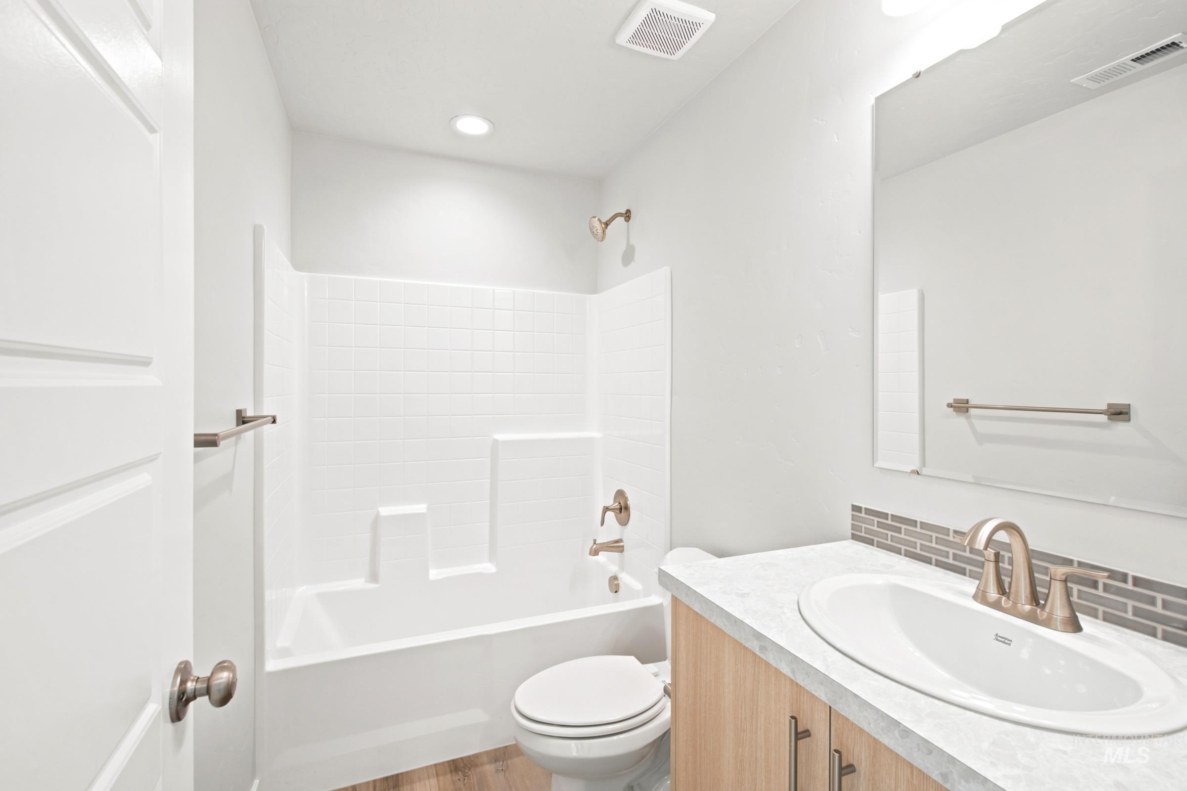 Bathroom featuring a built-in tub and shower combination with white tile surround