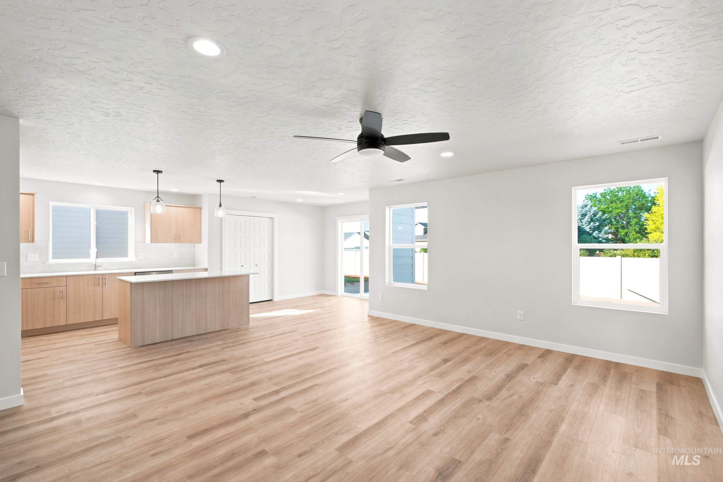 Open-concept living area featuring wood-finish flooring, a contemporary ceiling fan, and recessed lighting