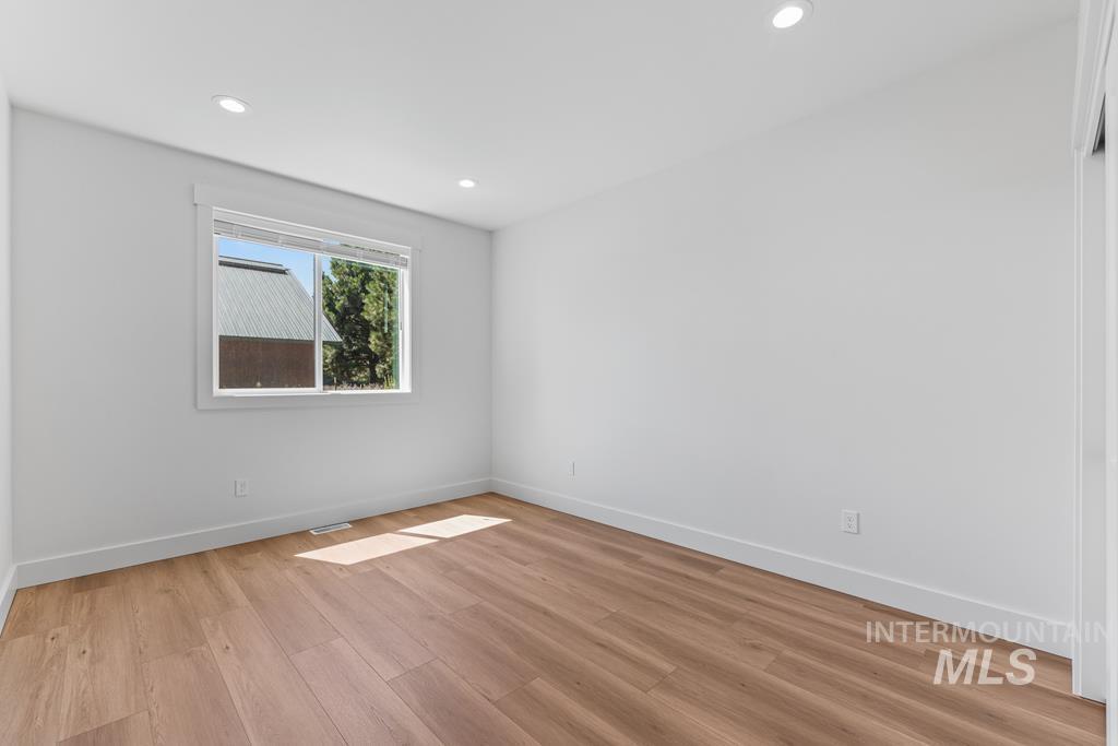 Empty room with light wood-style flooring and recessed lighting