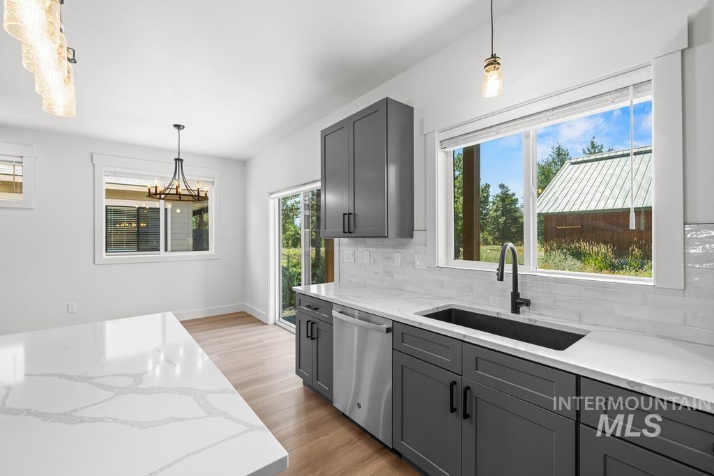 Kitchen featuring pendant lighting, gray cabinetry, light stone counters, and light wood-style flooring