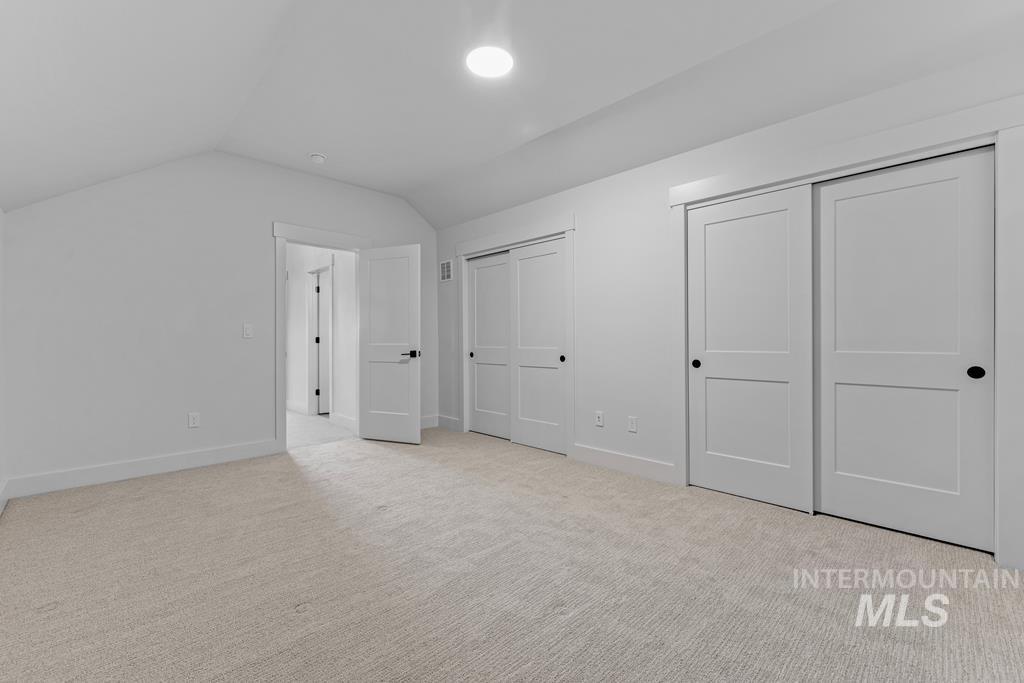 Bonus room featuring vaulted ceiling and light carpet