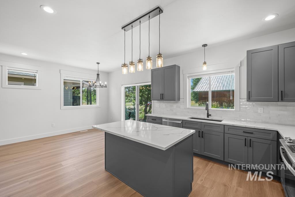 Kitchen featuring recessed lighting, gray cabinets, decorative light fixtures, a kitchen island, and light wood-style flooring