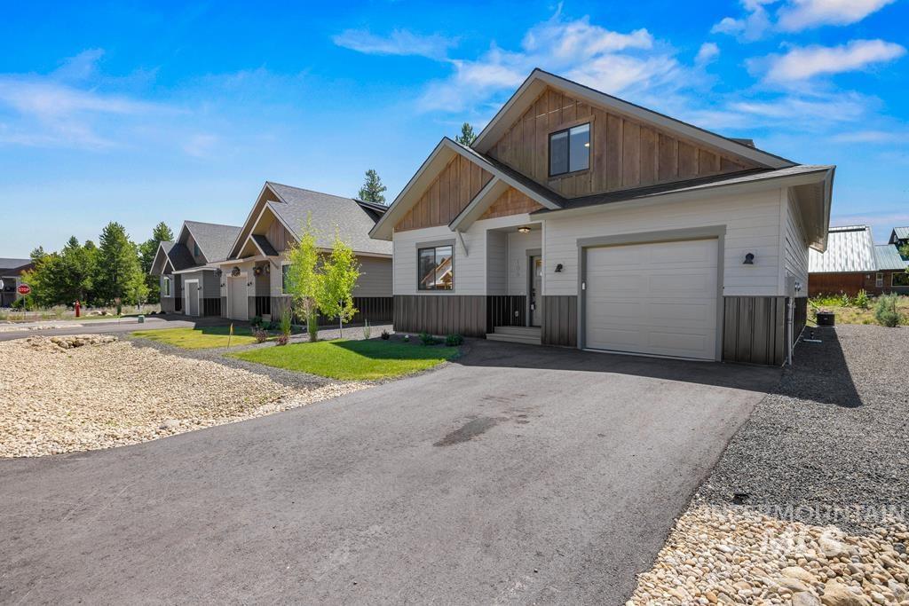 View of front facade featuring board and batten siding, asphalt driveway, a garage, and a residential view