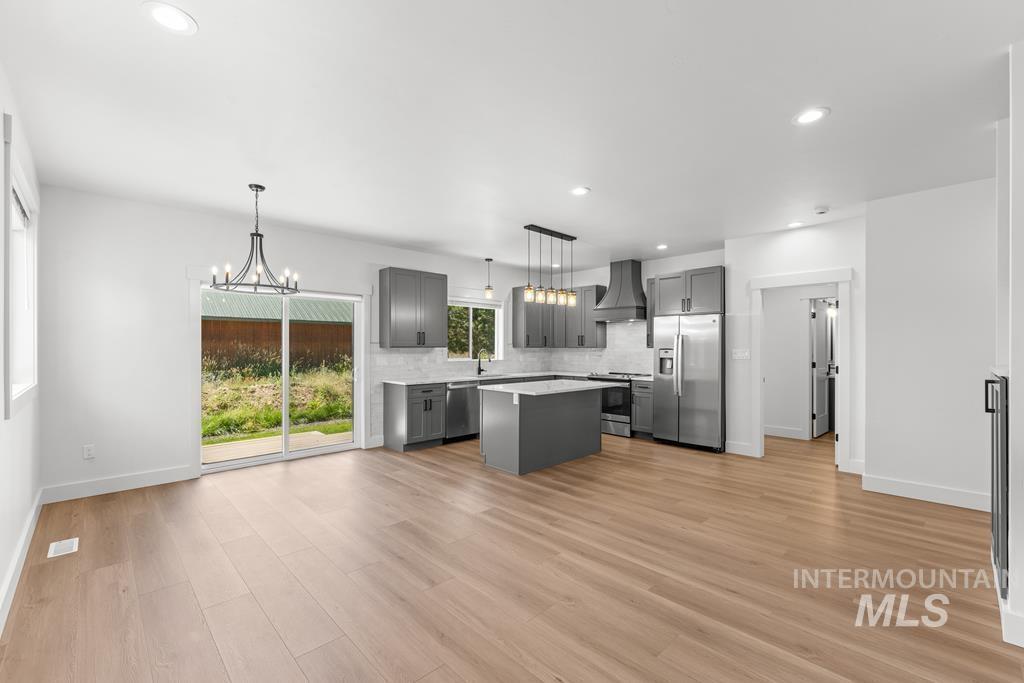 Kitchen with gray cabinetry, a kitchen island, tasteful backsplash, a chandelier, and stainless steel appliances
