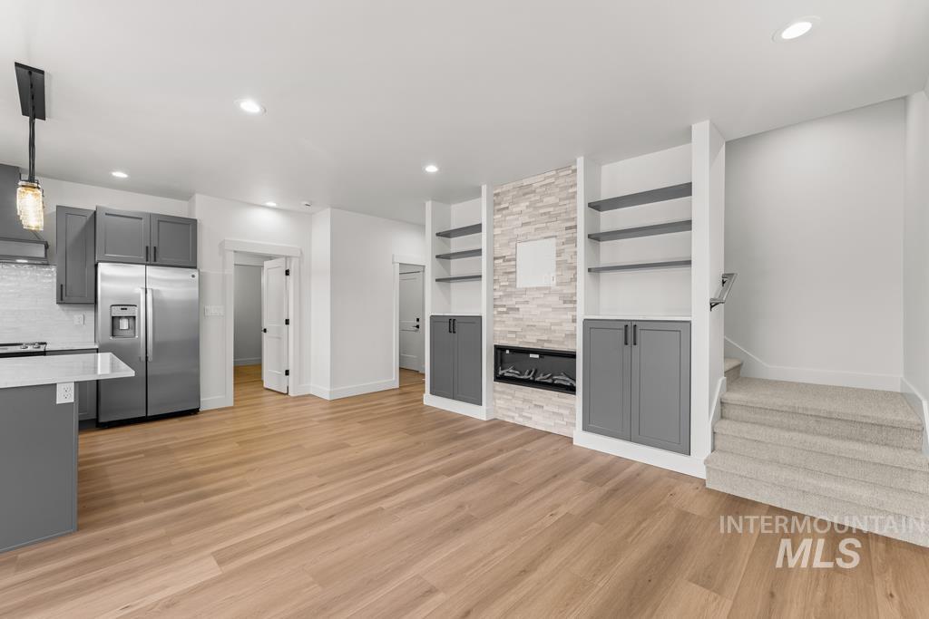 Kitchen with gray cabinetry, stainless steel fridge with ice dispenser, hanging light fixtures, recessed lighting, and exhaust hood