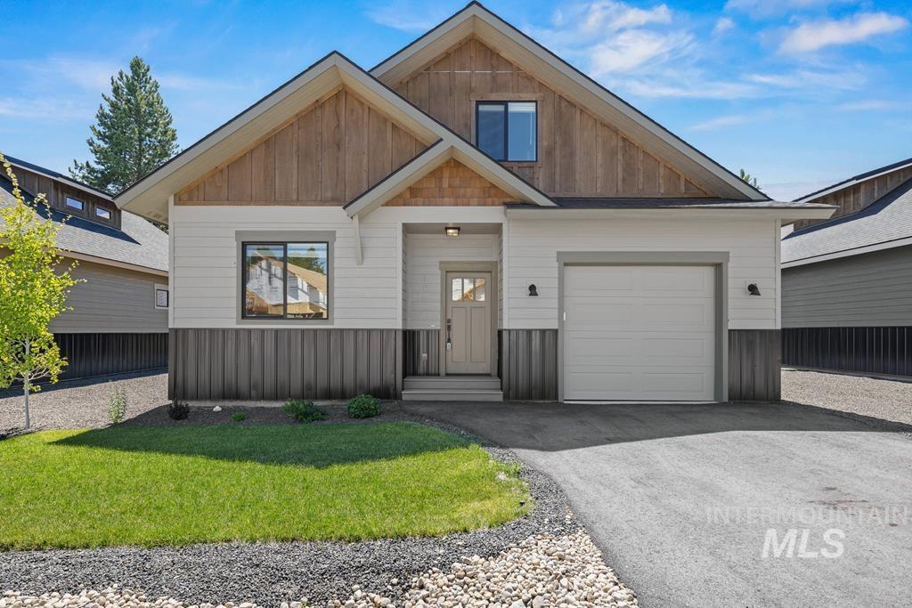 View of front of home with an attached garage, asphalt driveway, and a front yard