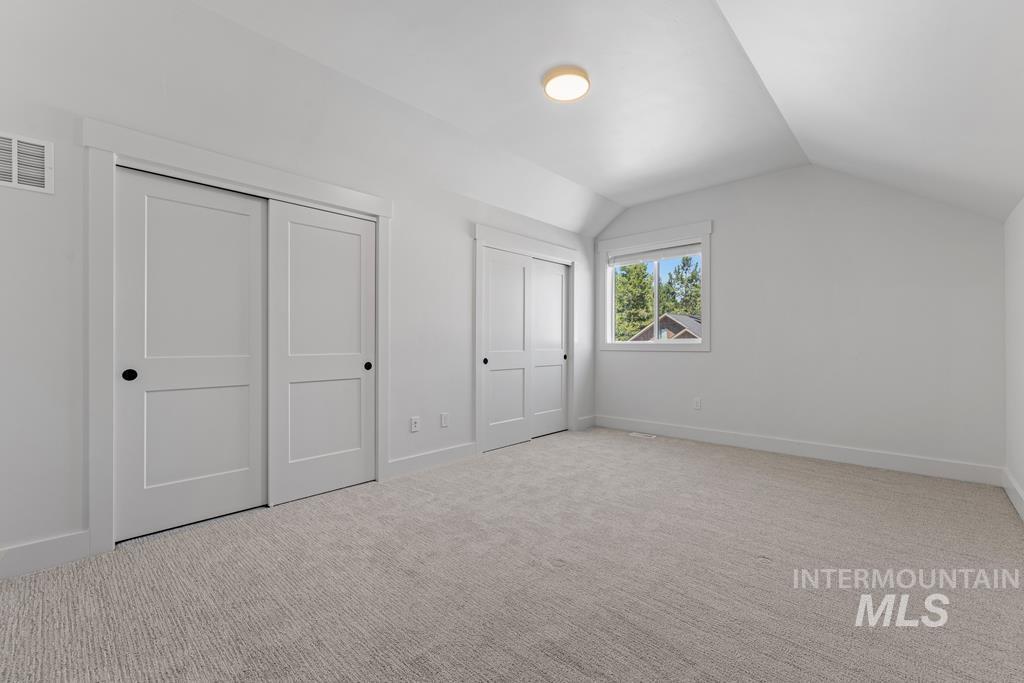 Additional living space featuring lofted ceiling and light colored carpet