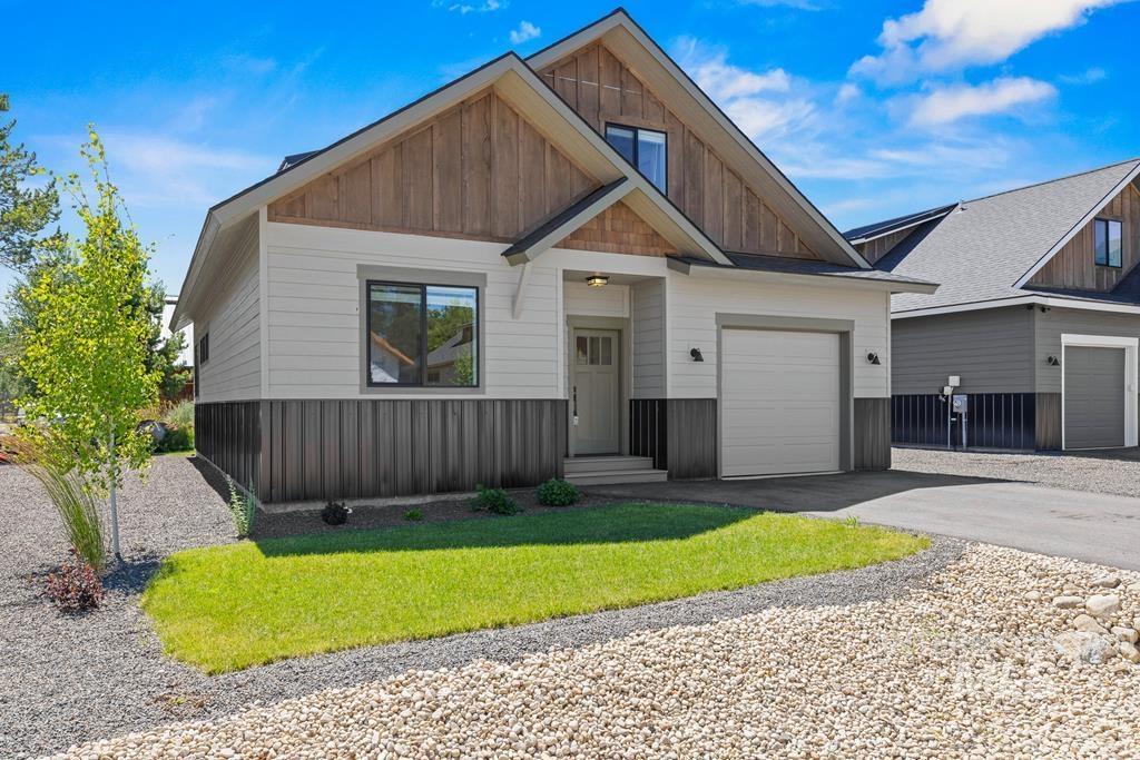 View of front of property featuring asphalt driveway, a front yard, board and batten siding, and an attached garage