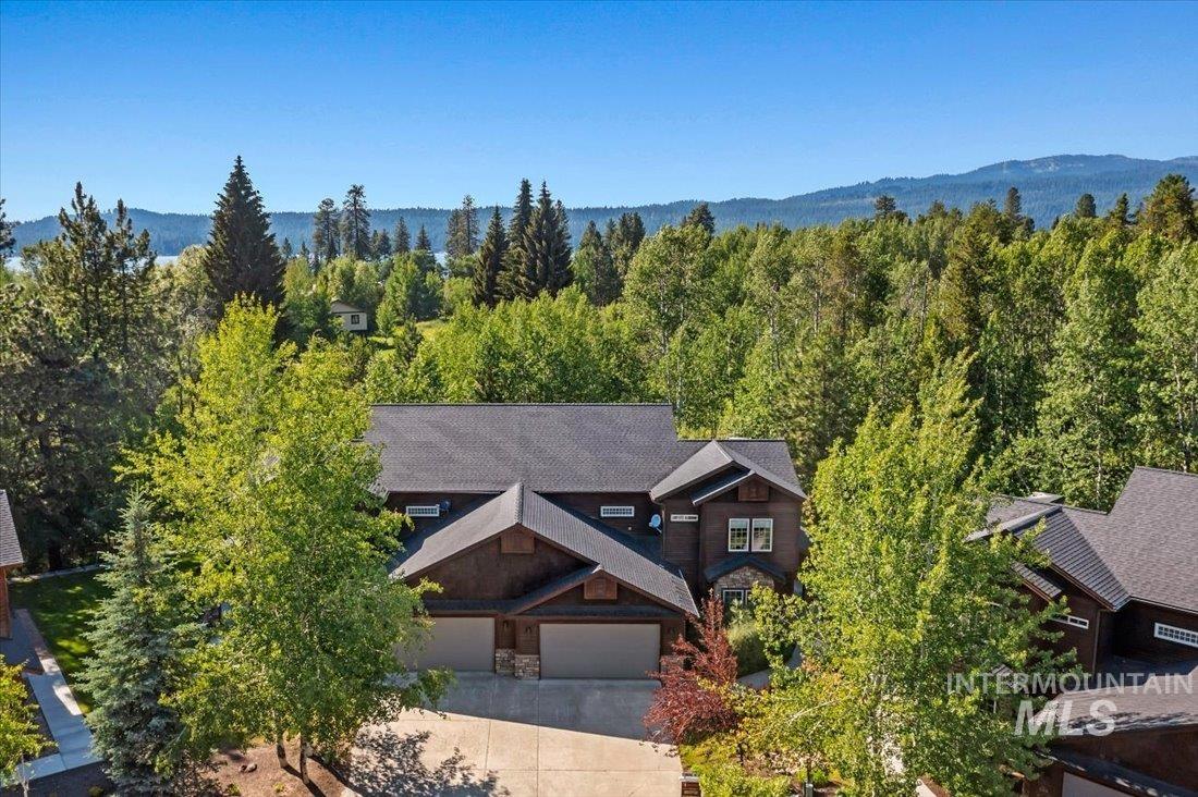 Aerial view of property and surrounding area with a heavily wooded area and a mountain backdrop
