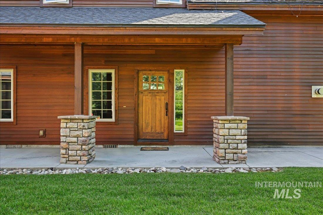 Entrance to property featuring a shingled roof and a porch