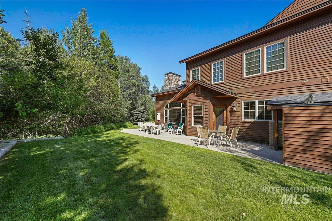 Rear view of property featuring a large patio and lawn with lots of privacy